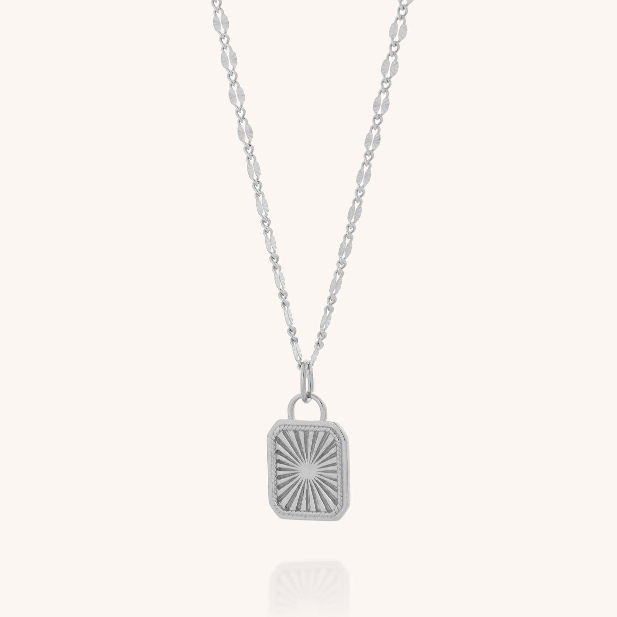 The Golden Dawn Necklace is a sterling silver piece with a rectangular sunburst pendant, displayed on a delicate oval-link chain that holds the center pendant vertically against a plain light background.