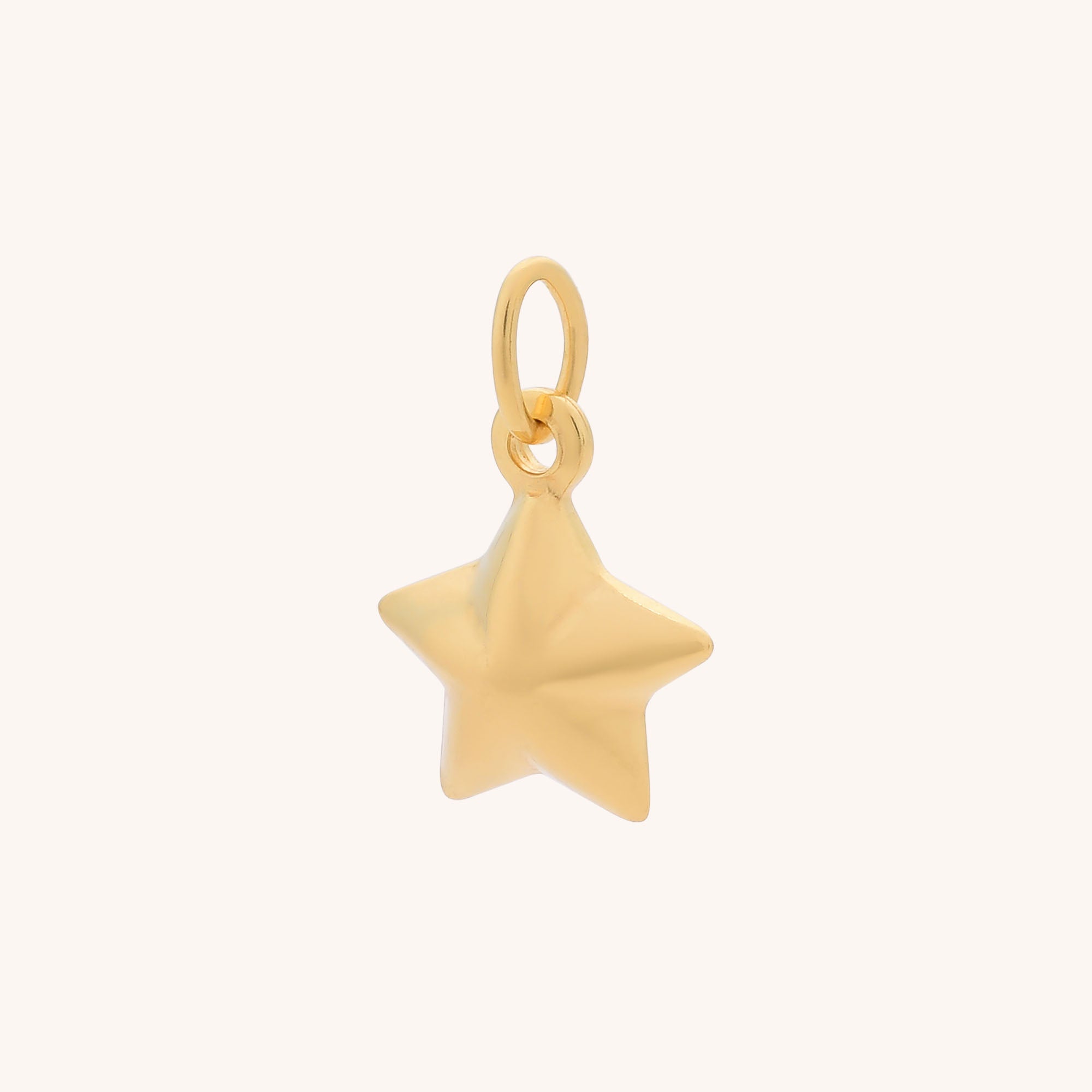 The Star Charm is a small, shiny gold pendant with celestial elegance. It features a top loop for attaching to a necklace or bracelet and is displayed against a plain light background.