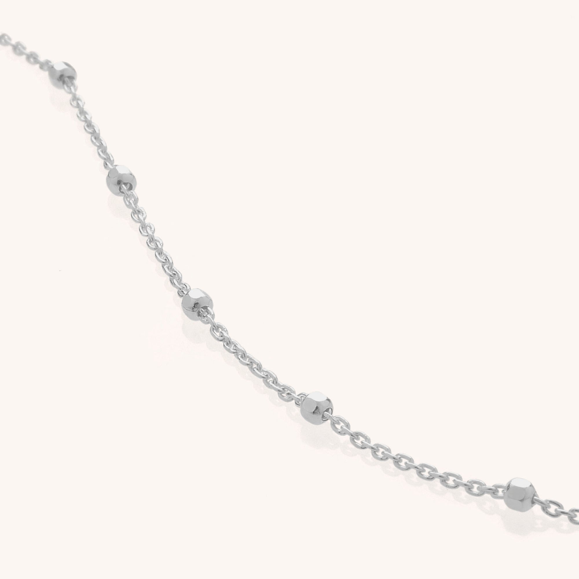 The Satellite Chain is a delicate necklace crafted from eco sterling silver, featuring small, faceted silver beads spaced evenly along the chain and displayed on a plain light background.