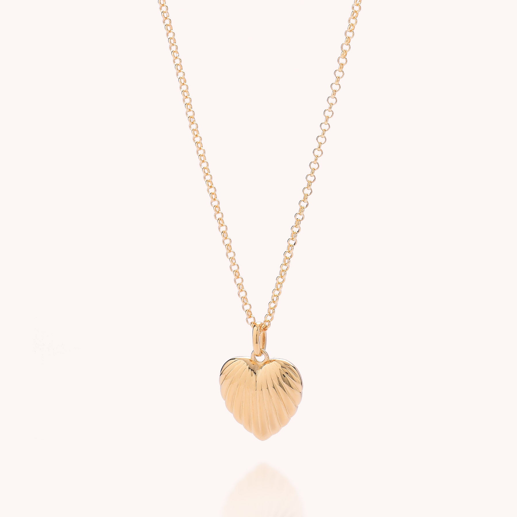 The Scalloped Heart Necklace features a gold-plated, ridged heart-shaped pendant on a delicate chain, displayed against a light background.