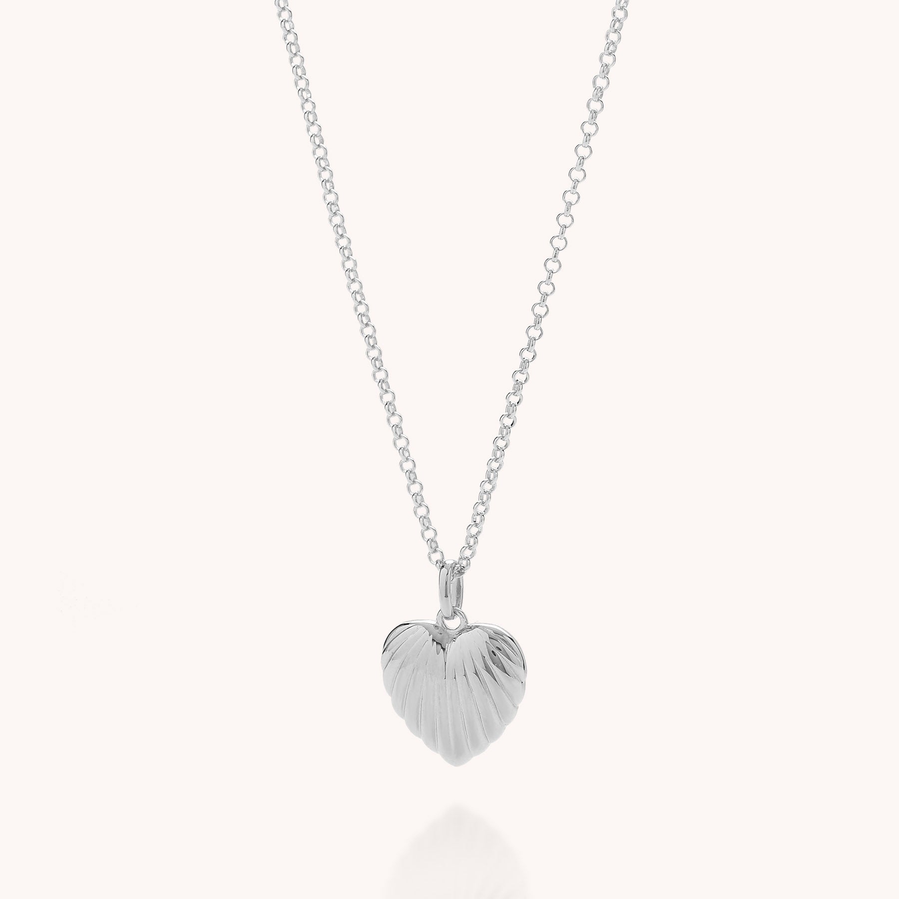 The Scalloped Heart Necklace is a delicate sterling silver piece with a small, textured, heart-shaped pendant featuring a ridged design, shown against a plain light background.