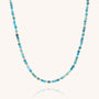 The Jewel Bead Birthstone Necklace - December features delicate round turquoise beads and tiny gold accents on eco-friendly sterling silver, arranged in a simple, elegant design against a white background.
