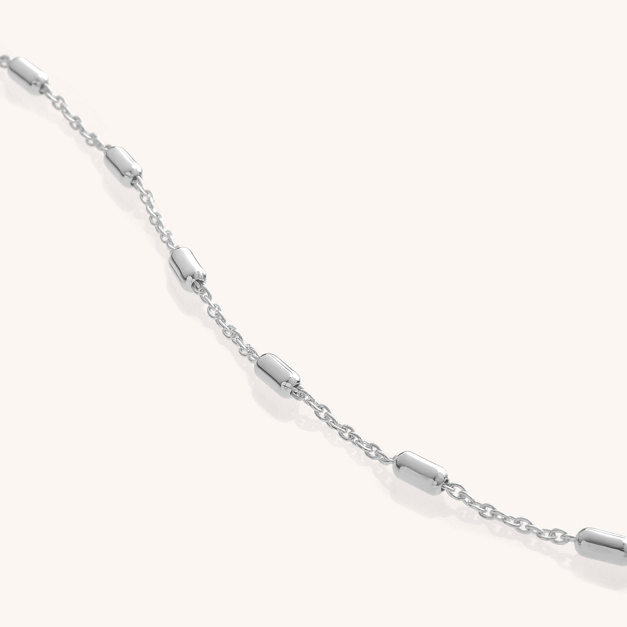 The Tubular Satellite Chain is a delicate Eco Sterling Silver bracelet featuring evenly spaced small cylindrical beads, shown on a light, neutral background.