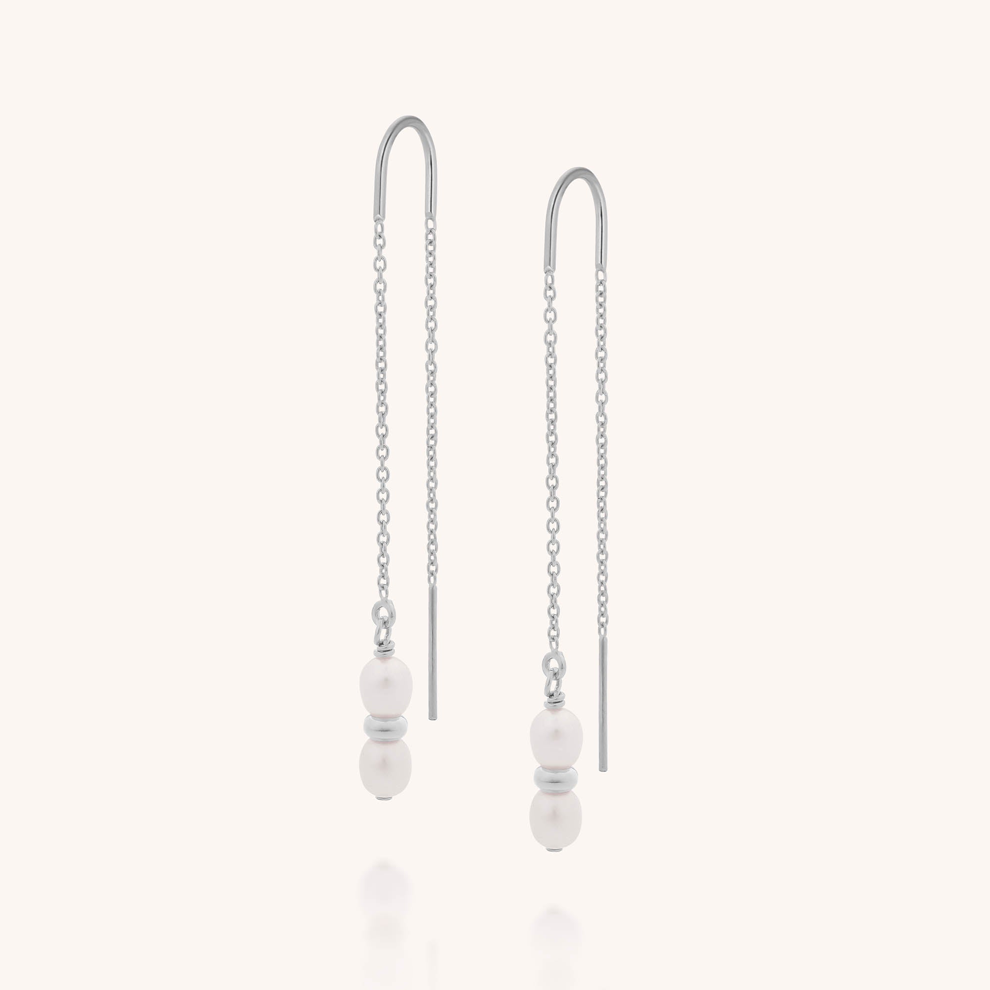 The Ellen Pearl Fall Earrings are sterling silver threaders with delicate chains, each adorned with two white freshwater pearls separated by a small silver spacer near the ends.