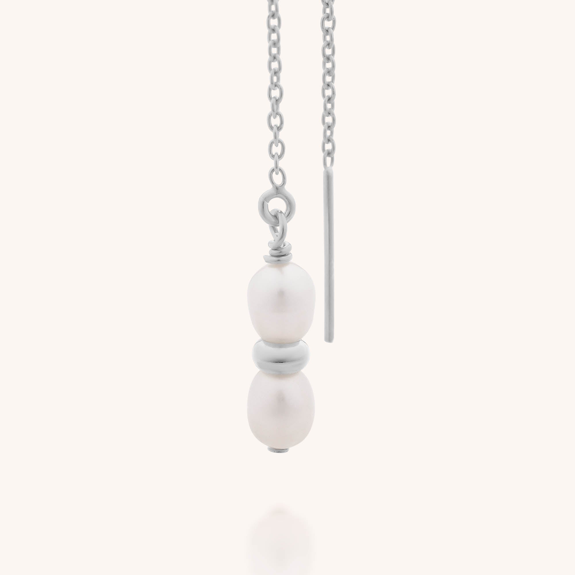 The Ellen Pearl Fall Earrings feature two vertically stacked freshwater pearls on a delicate sterling silver drop, accented with a thin silver bar, showcased against a plain light background.