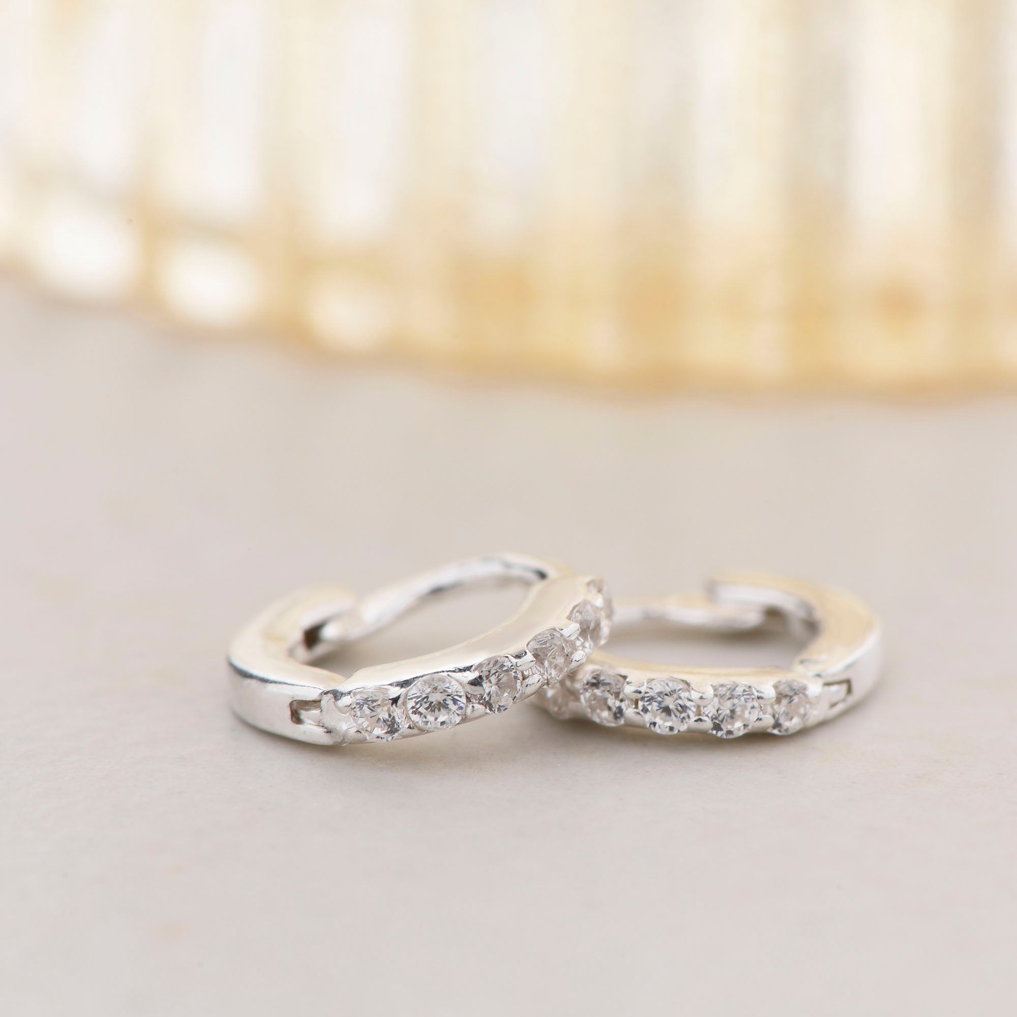 Pair of cz ear hoops next to vase