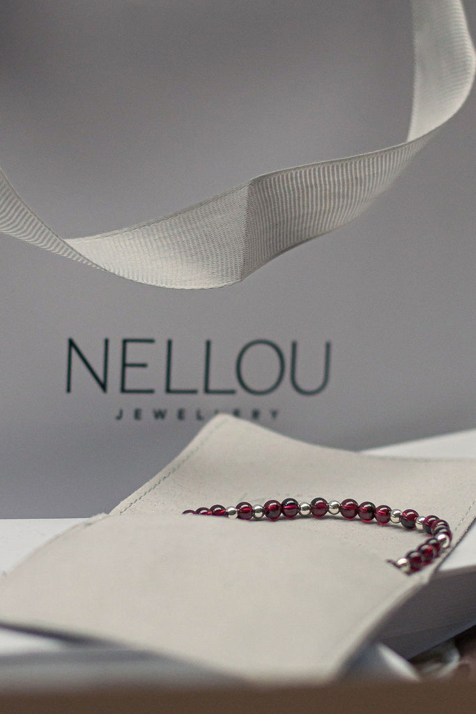 Gift bag with garnet birthstone necklace poking out of a Nellou gift pouch