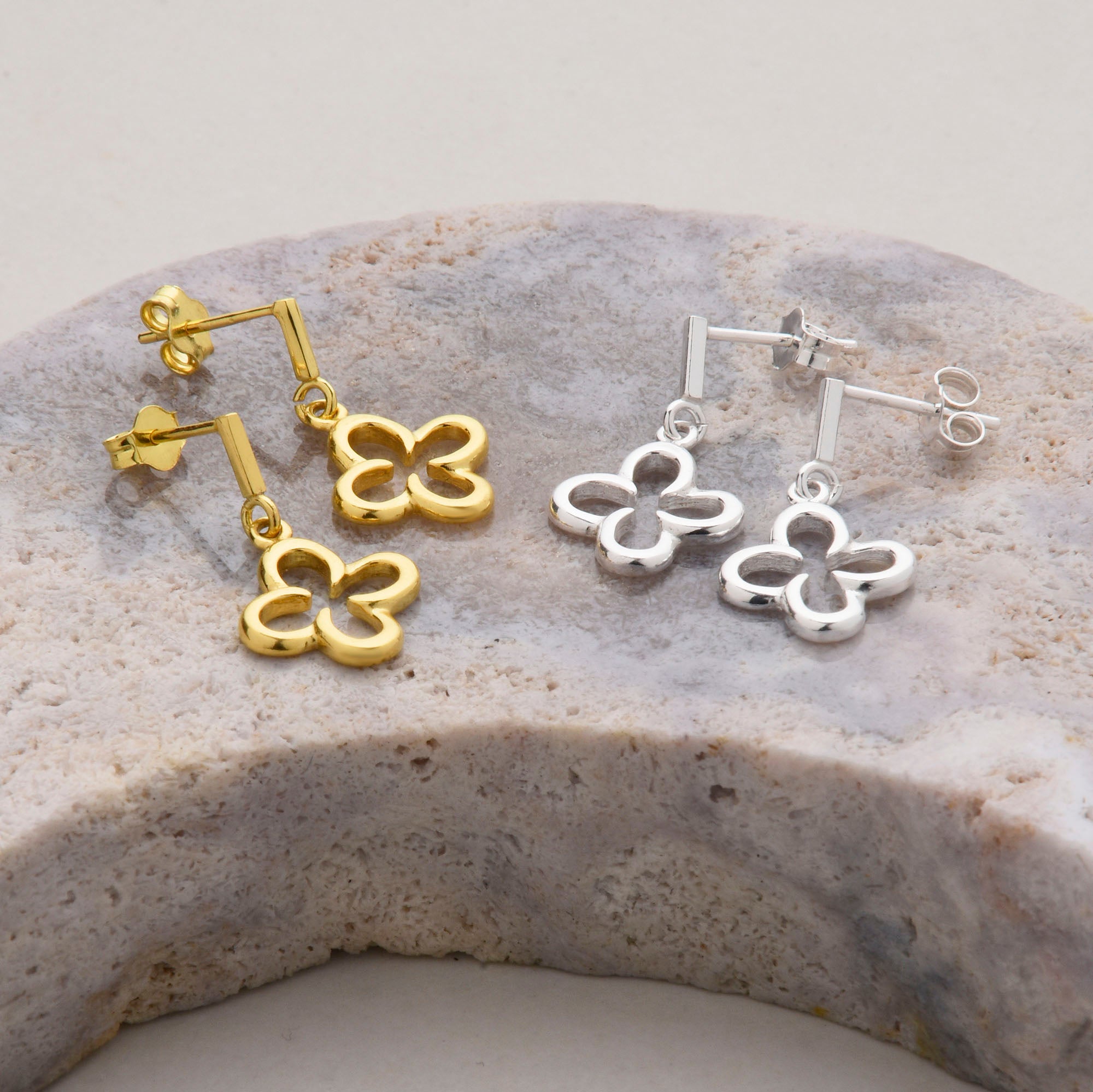 silver and gold ear drops in a clover design on a pink amethyst