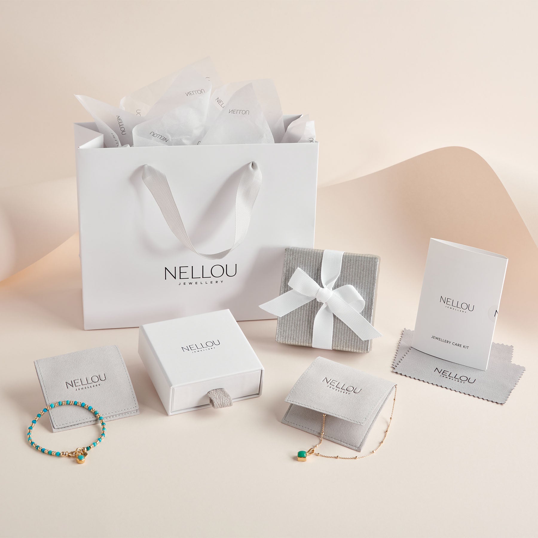 The Luxury Gift Wrapping features a branded Nellou gift bag, jewellery boxes, pouches, a care kit, and two delicate bracelets—arranged to create an elegant gifting scene on a soft beige background.