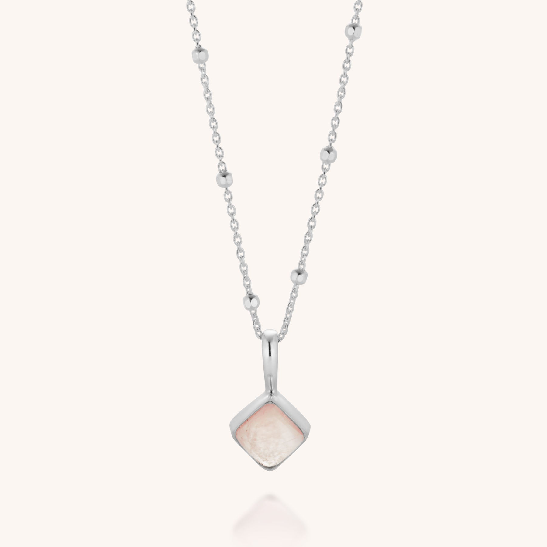 The Rose Quartz Diamond Necklace is a sterling silver piece with small bead accents, showcasing a square rose quartz-like pendant in a polished silver frame, evoking gentle healing and elegance.