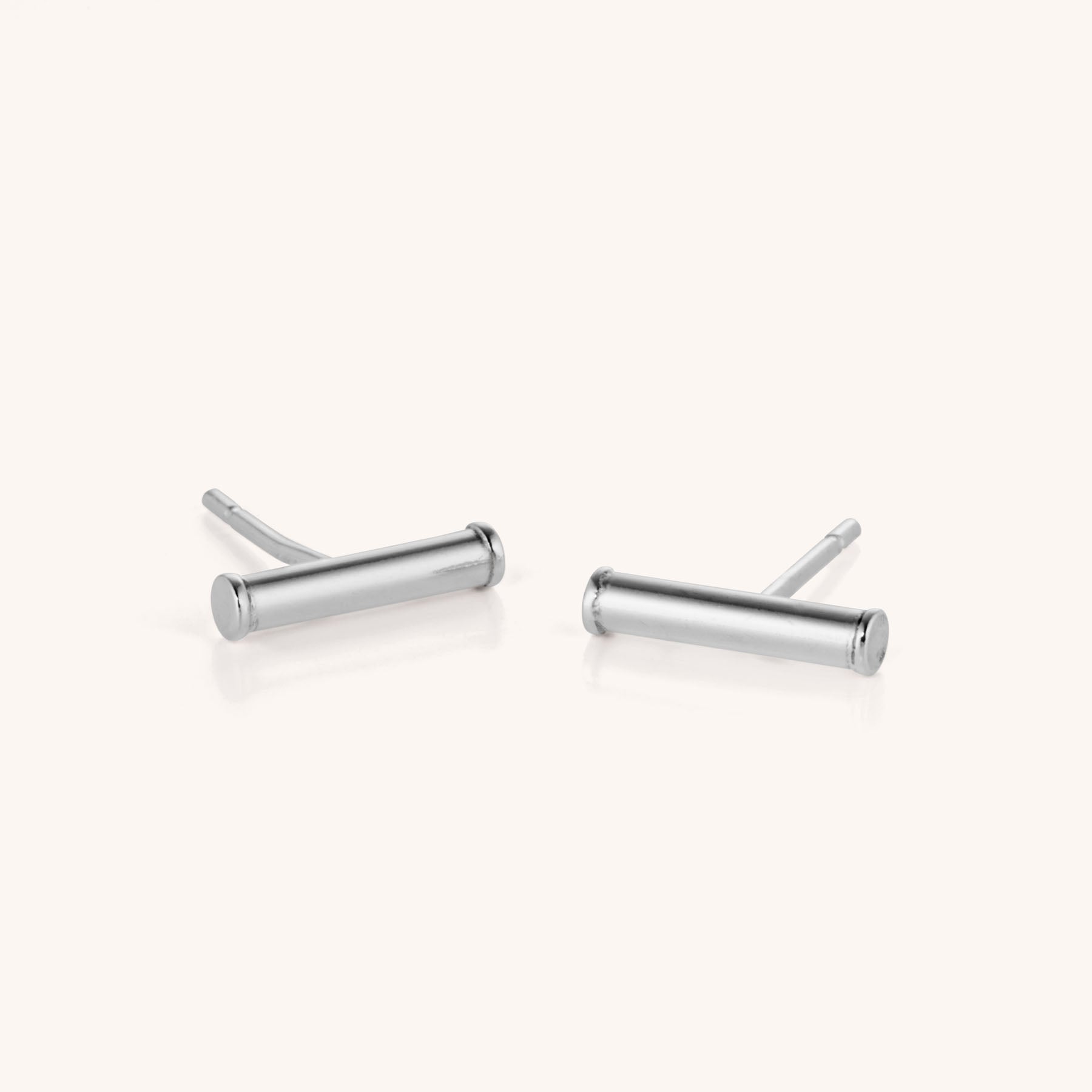 The Bar Stud Earrings are shown on a plain, light background. These minimalist, hypoallergenic earrings feature a sleek horizontal cylindrical bar design in silver.
