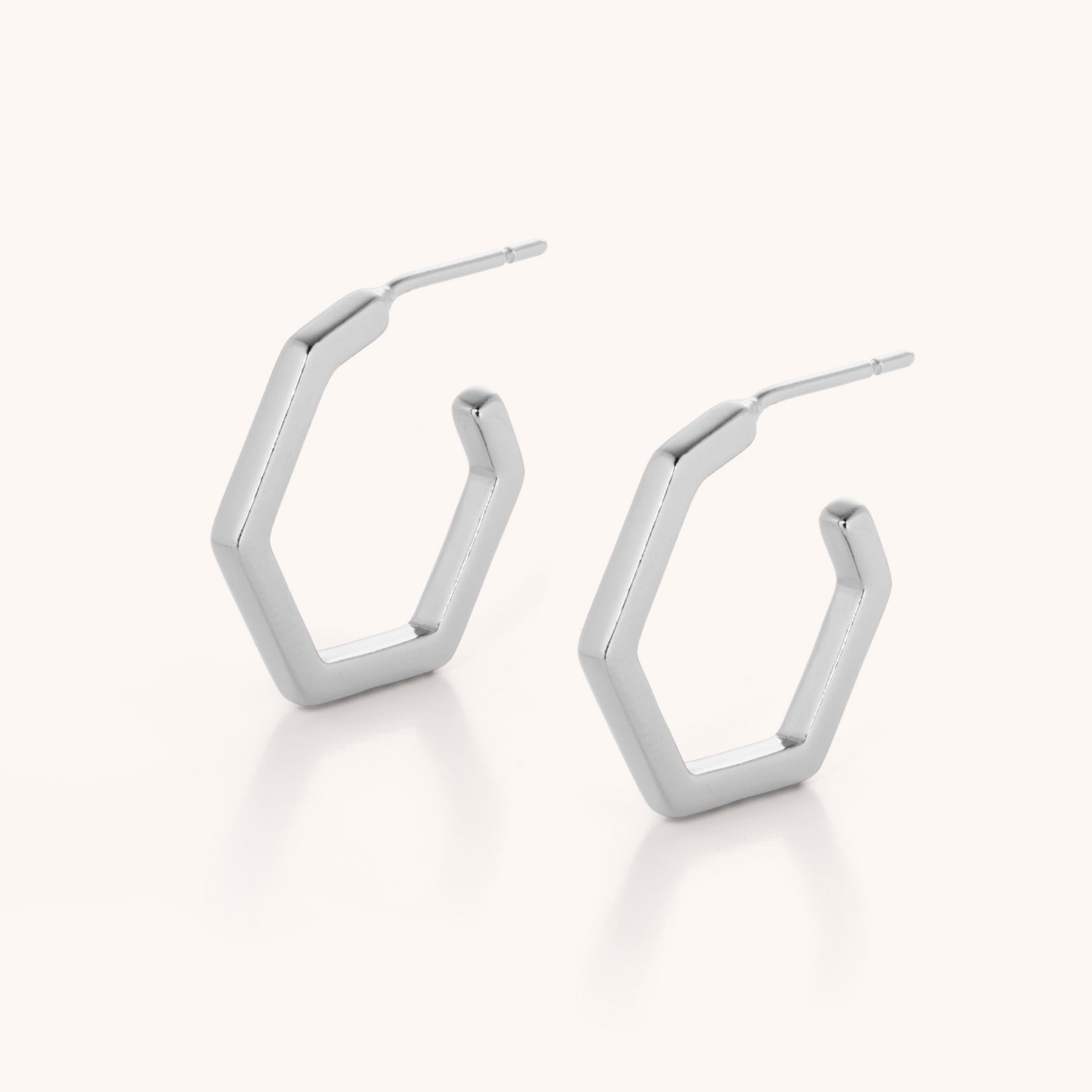 The Hex Hoop Earrings feature a minimalist hexagonal design in solid silver, shown against a plain white background.