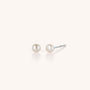 The Tiny Pearl Button Stud Earrings feature a timeless design with silver posts, shown on a plain white background—ideal for effortless everyday wear.
