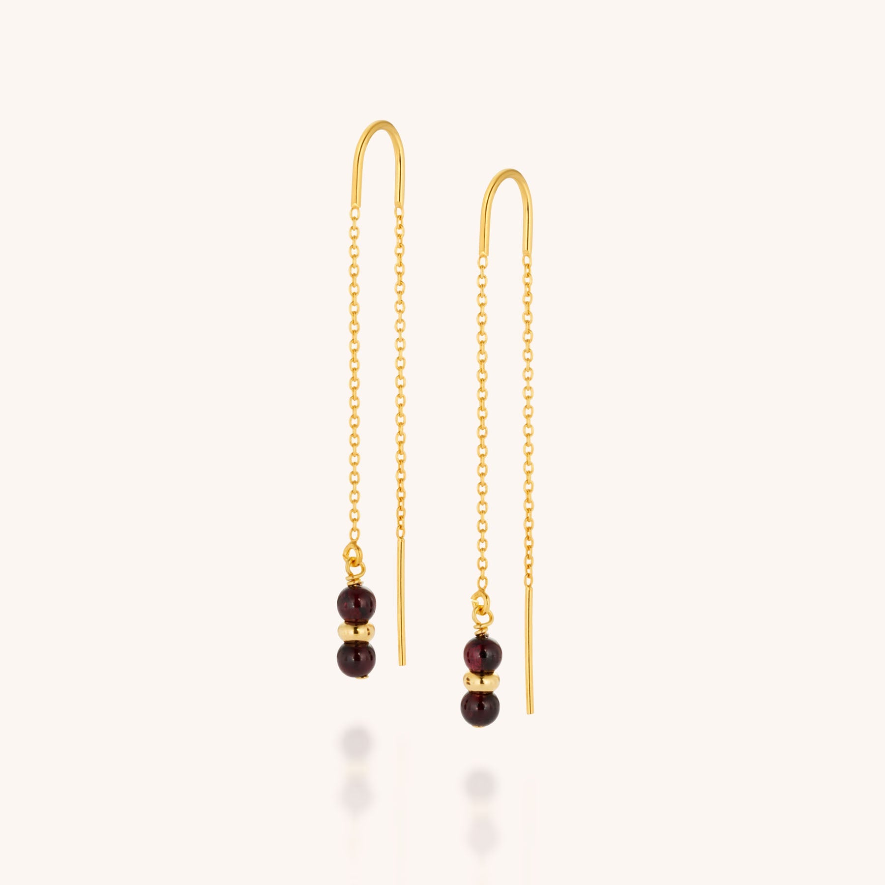 The Fall Earrings Birthstone January feature gold threader chains, each adorned with three small round garnet beads, displayed on a plain light background—perfect as elegant birthstone earrings.
