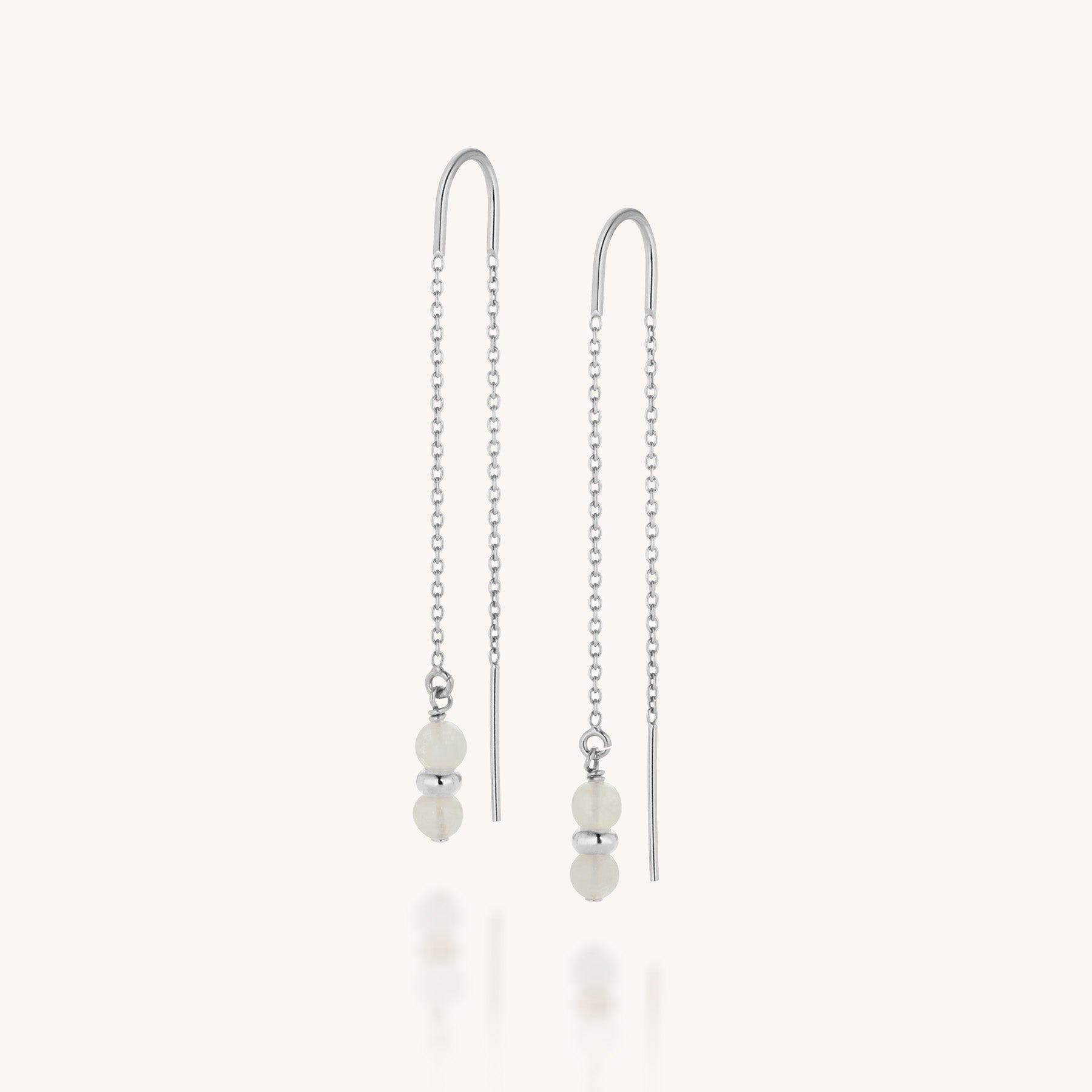 A pair of Fall Earrings Birthstone June: silver threader Moonstone earrings featuring delicate chains with two small white beads and a silver accent bead at the base. Their minimalist design makes them perfect for birthstone jewelry lovers.