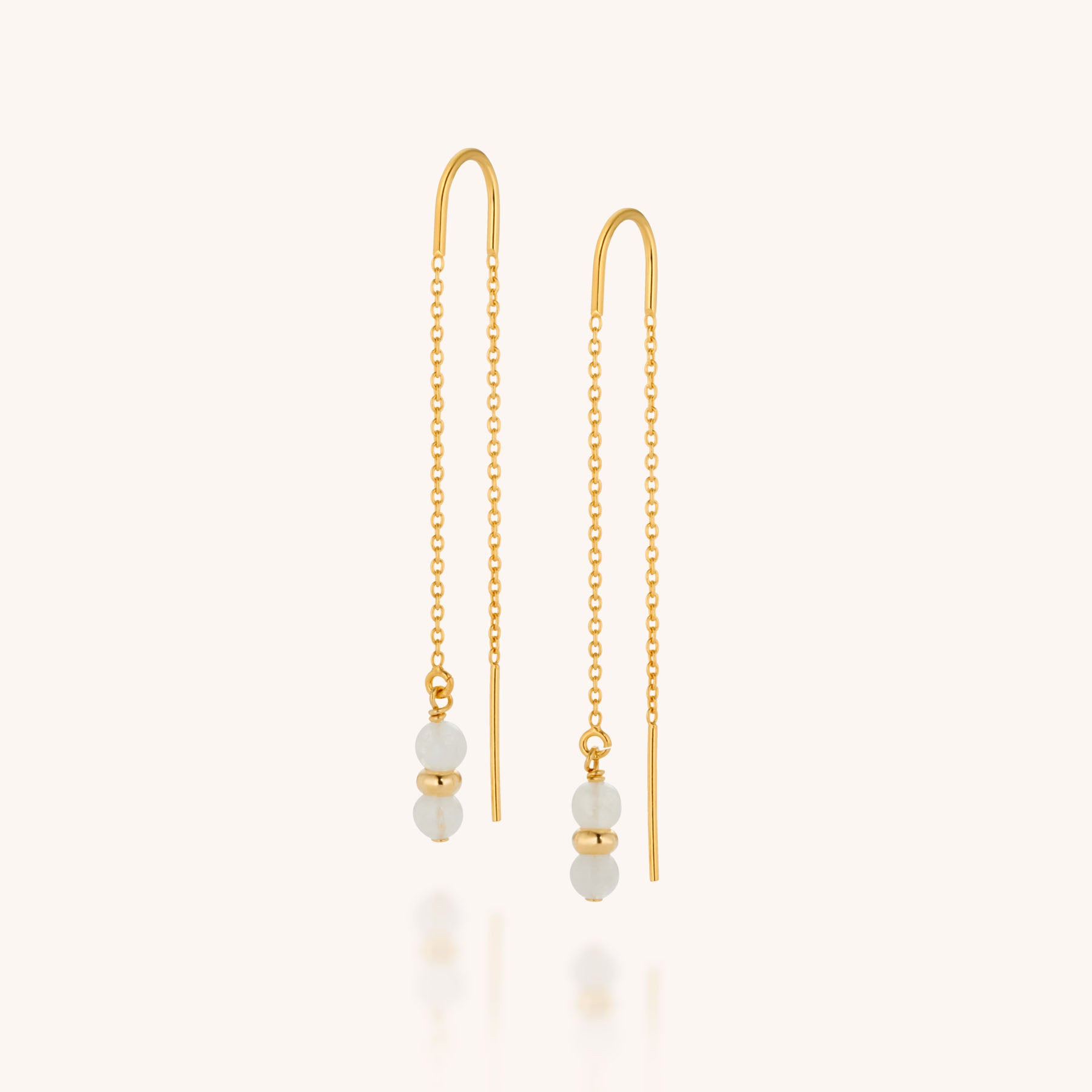 Fall Earrings Birthstone June: Minimal gold threader earrings feature delicate chain links and two small white beads separated by a gold bead at the end, evoking refined gemstone jewelry charm against a pale backdrop.