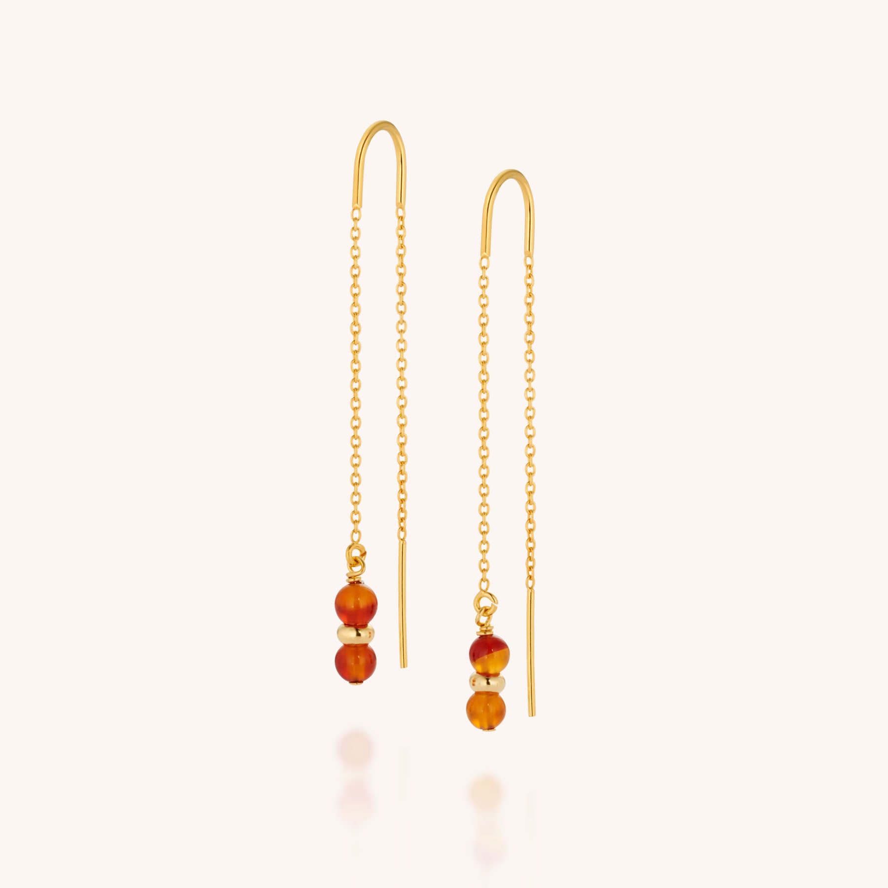 The Fall Earrings Birthstone July are gold chain threaders, each adorned with two small carnelian gemstone beads at the ends, showcased against a light background.