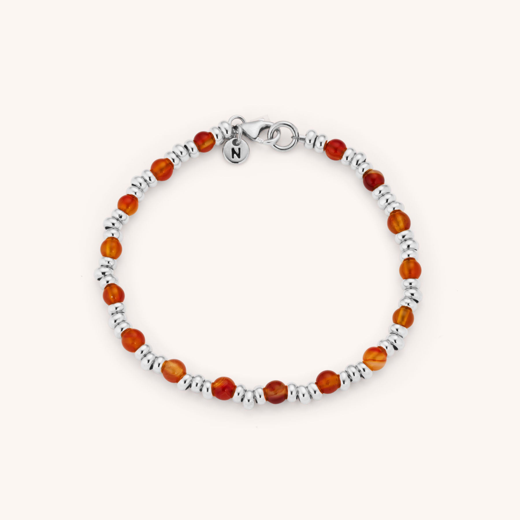 The Gem Bracelet July Birthstone is a beaded eco-silver bracelet with alternating round amber and silver beads, carnelian accents for July’s birthstone, a lobster clasp, and a small round charm engraved with an N.
