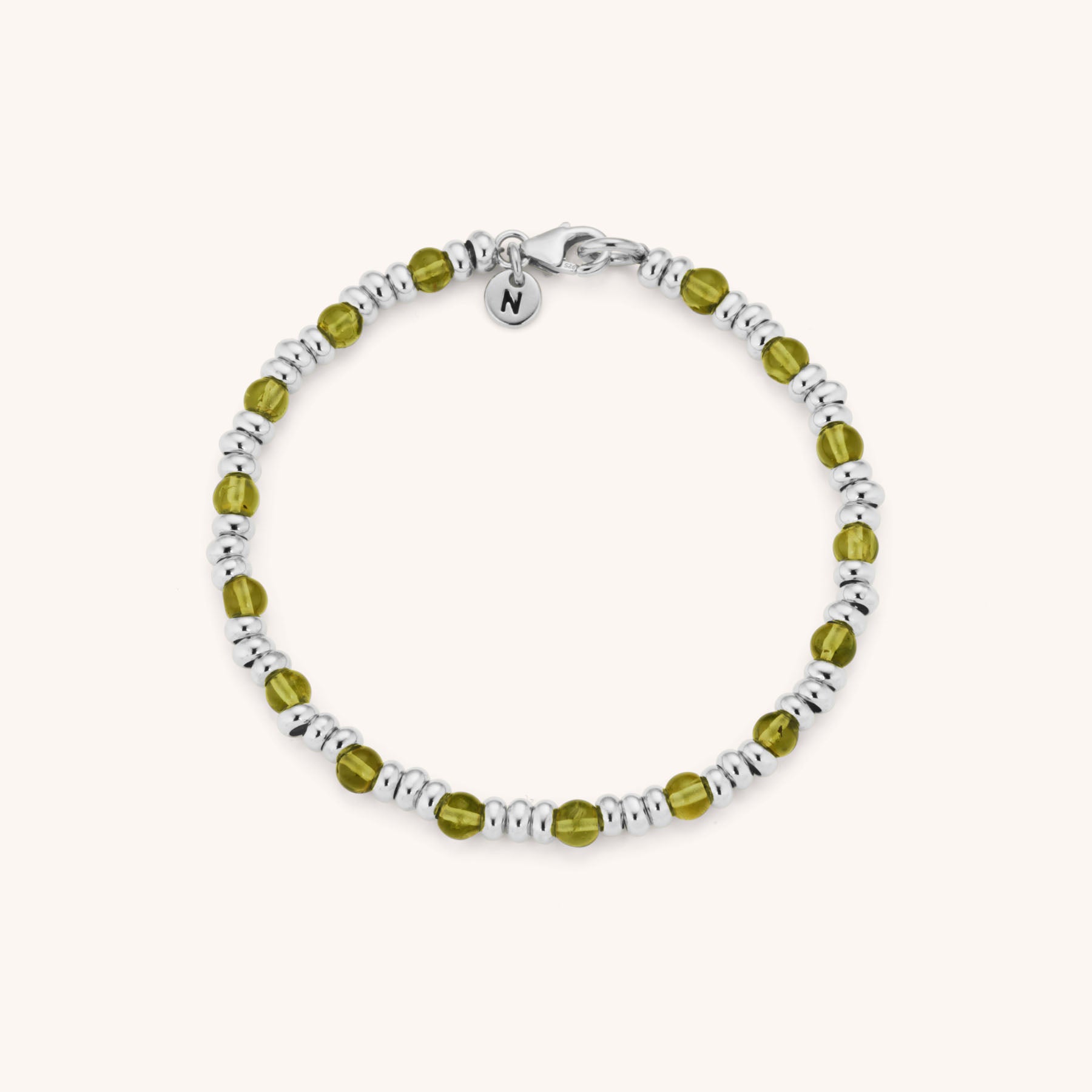 The Gem Birthstone Bracelet showcases alternating eco sterling silver and olive green gemstone beads, finished with a small round charm engraved with the letter N near the clasp, all displayed on a light background.
