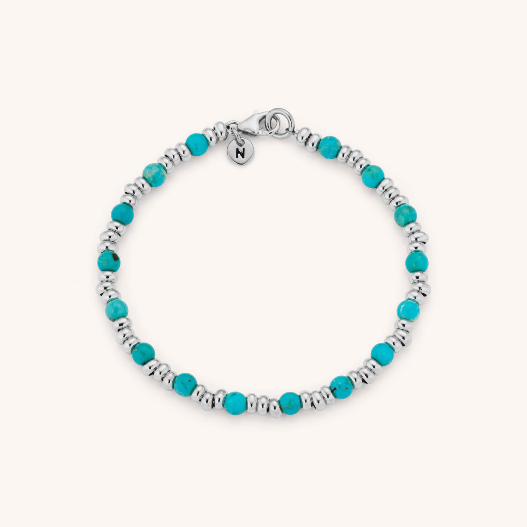 The Gem Bracelet December Birthstone features eco-silver with alternating turquoise and silver beads, finished with a small engraved N charm—an ideal gift for December birthstone lovers.