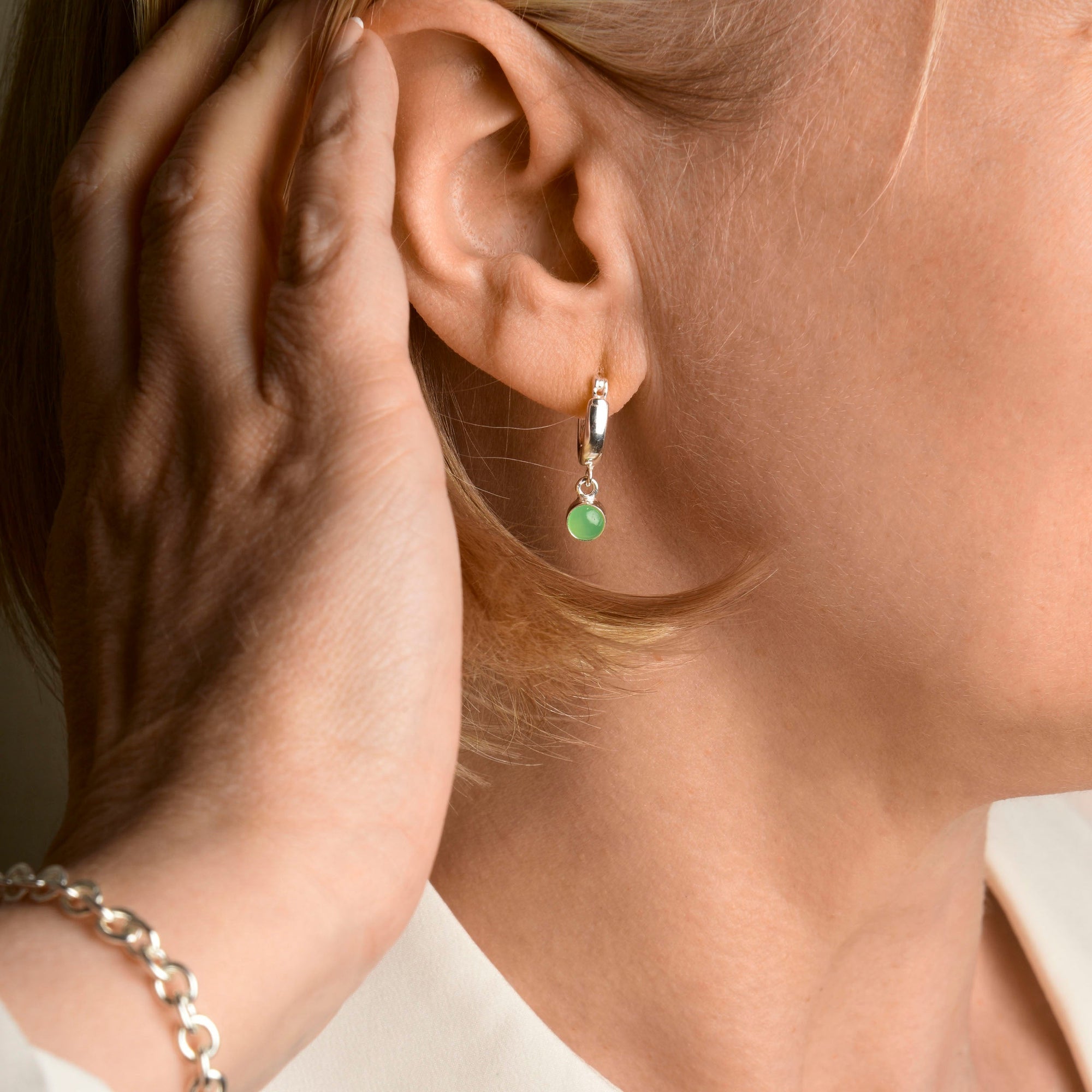 Hand brushing ear with birthstone earring