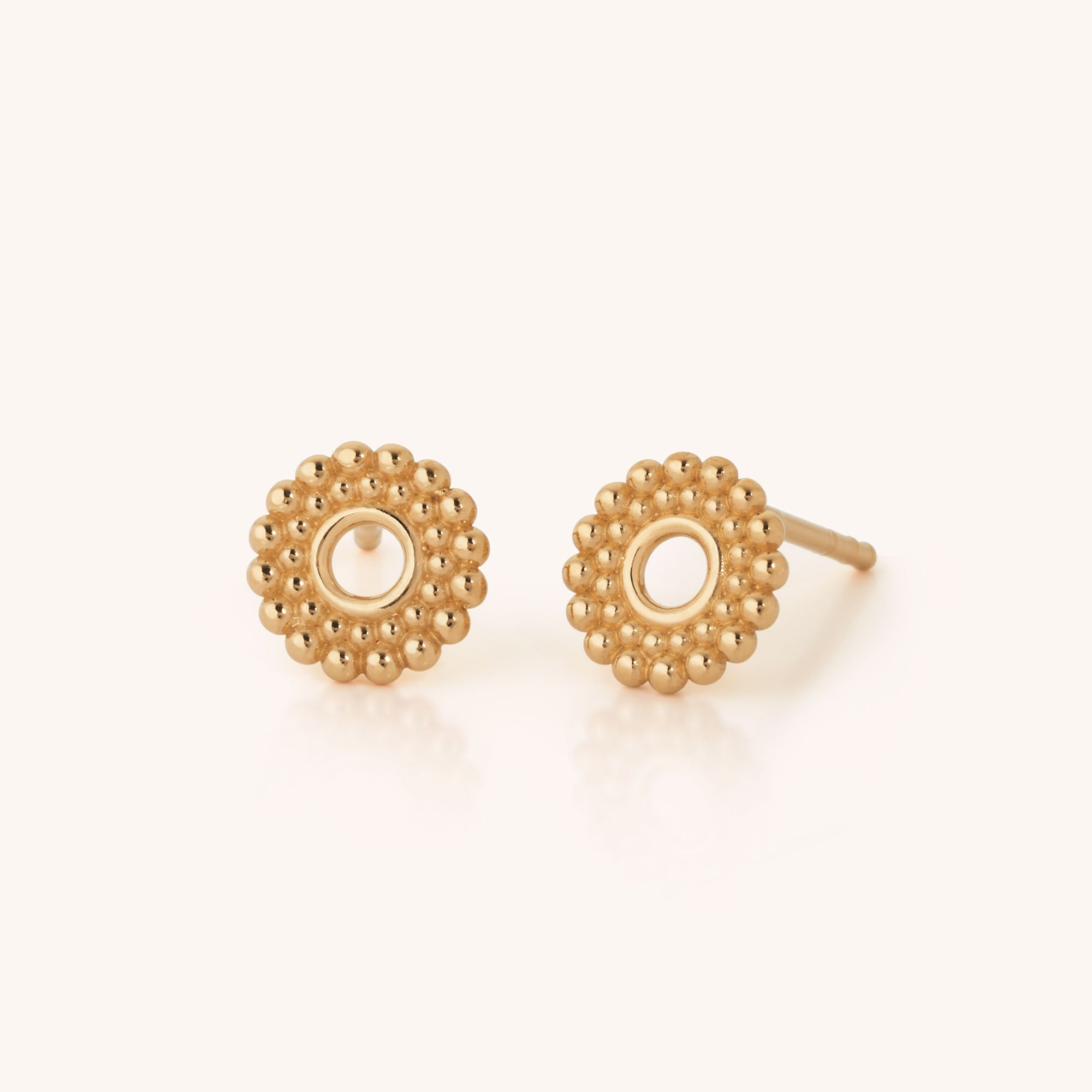 A pair of Beaded Halo Ear Studs featuring a small, round gold plated design with a beaded flower-like edge and an open center, displayed on a light background.