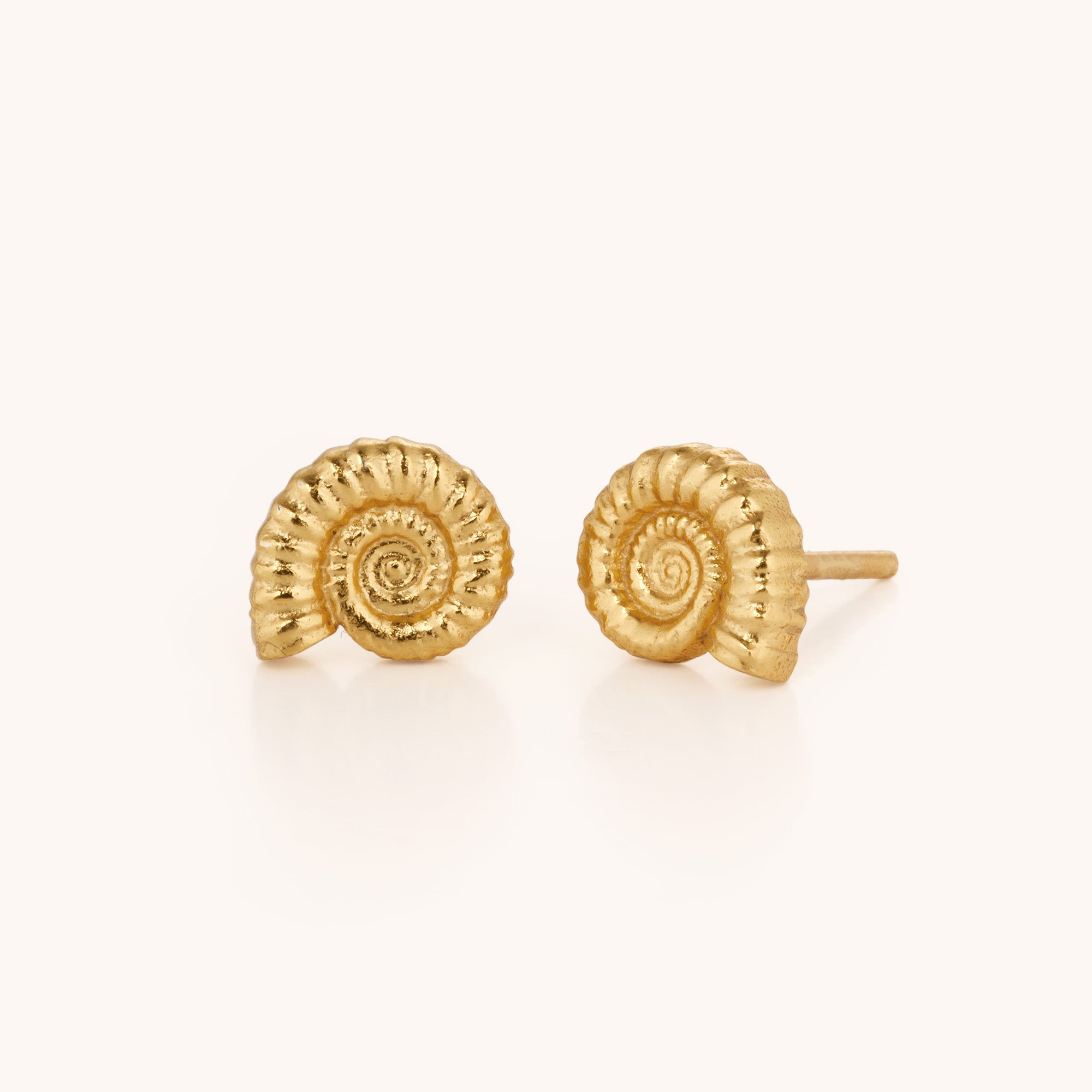 Ammonite Earrings: Small, artisan-crafted gold stud earrings shaped like spiral seashells, displayed on a plain, light background.