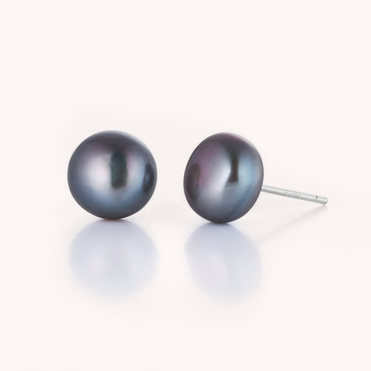 A pair of Large Pearl Button Stud Earrings with silver posts is displayed on a white background with a subtle reflection.