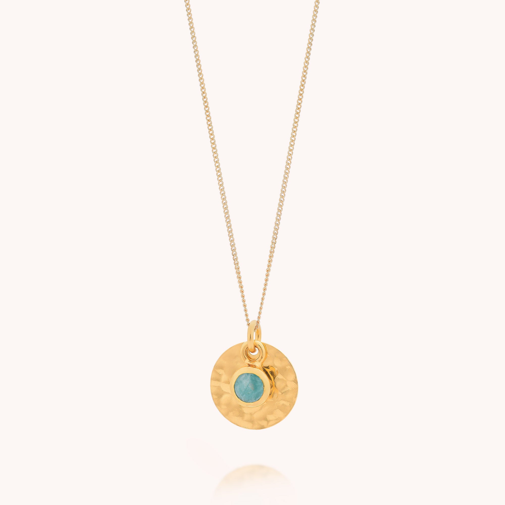Amazonite Luna Disc Necklace displayed against a light background, featuring a textured, hammered round pendant inspired by jewelry design with a small amazonite gemstone set at the center.