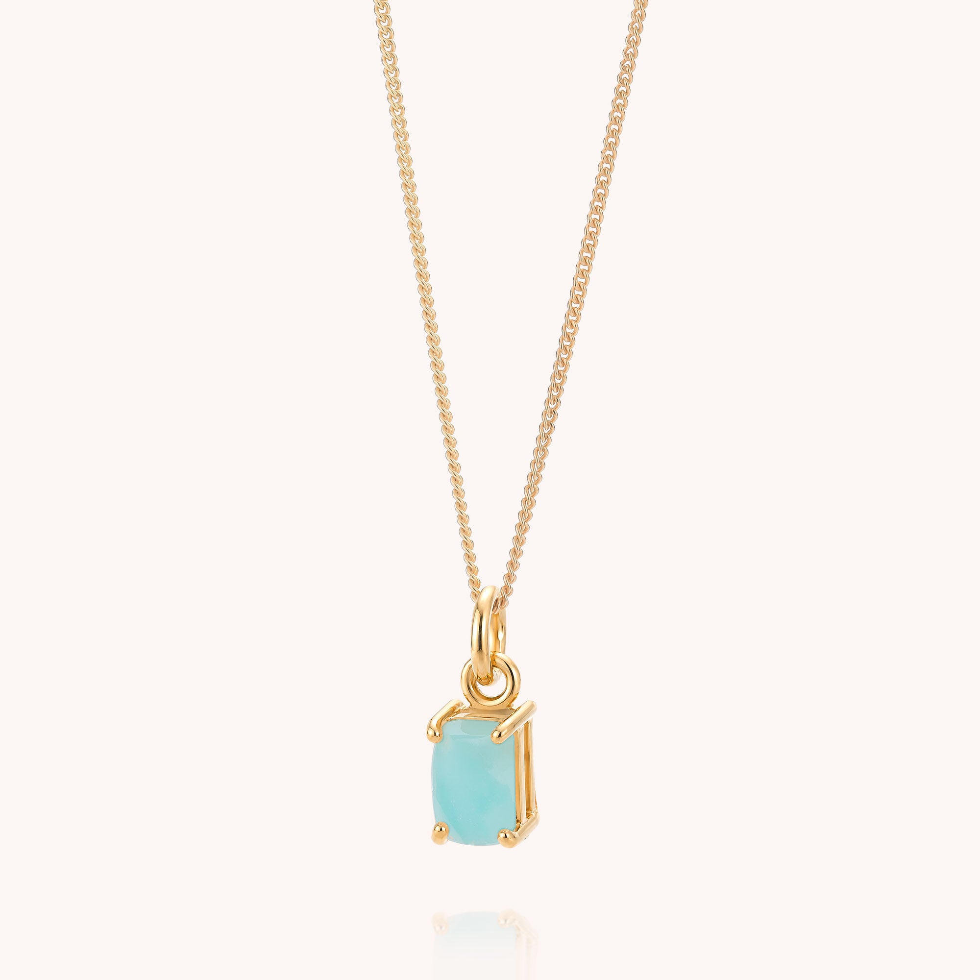 The Amazonite Octavia Necklace showcases a delicate gold chain adorned with a small, rectangular light blue Amazonite gemstone pendant, set in an elegant gold prong setting and displayed against a simple, light background.