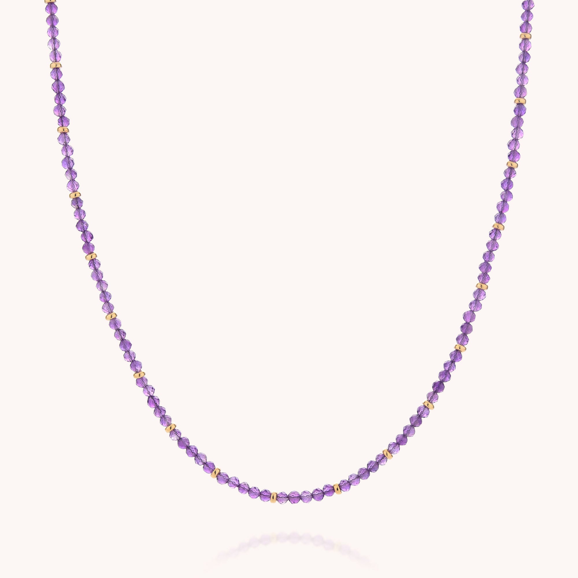 Introducing the Amethyst February Birthstone Orbit Necklace—a charming handcrafted piece adorned with small round purple amethyst beads and delicate gold accents, thoughtfully arranged in an elegant pattern on a light backdrop. This exquisite necklace is perfect for anyone who cherishes February’s birthstone.