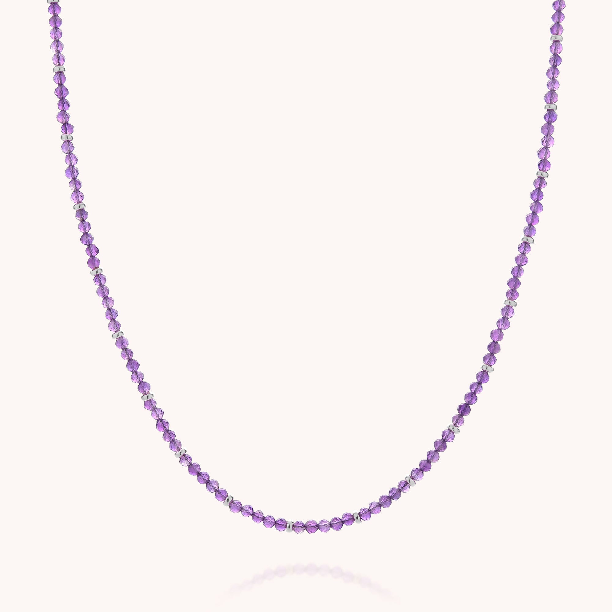 The Amethyst February Birthstone Orbit Necklace is a delicate handcrafted jewelry piece, featuring alternating small purple and clear round beads, displayed against a plain white background.