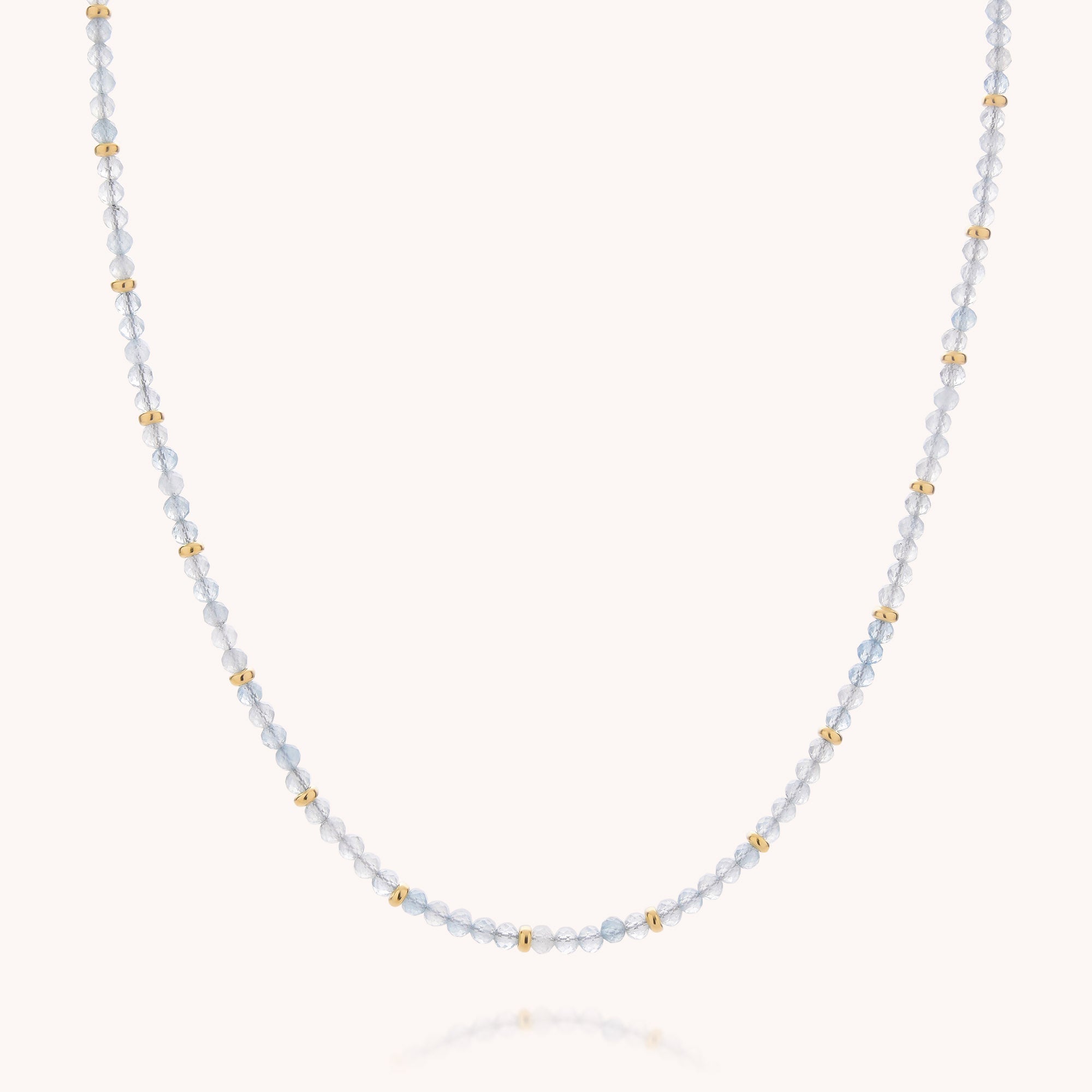 The Aquamarine March Birthstone Orbit Necklace features small translucent blue aquamarine beads paired with evenly spaced gold accents, arranged in a simple, elegant design against a plain background—an exquisite piece of handcrafted jewelry perfect for celebrating the March birthstone.