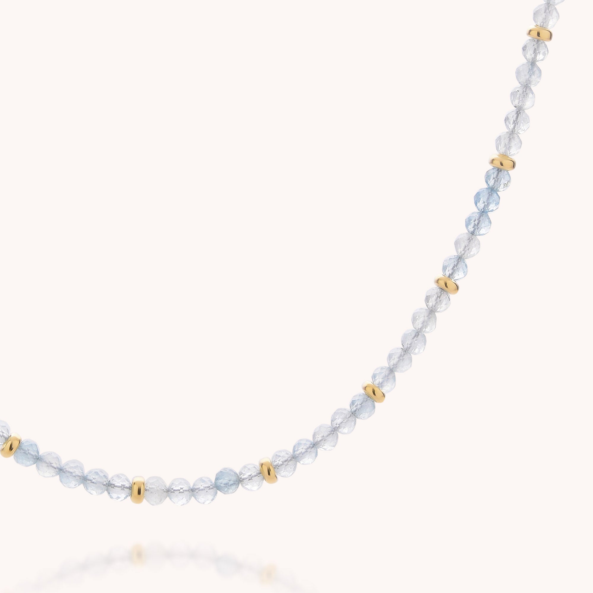 A close-up of the Aquamarine March Birthstone Orbit Necklace, featuring delicate, round light blue beads and evenly spaced gold accents on a white background—perfect for celebrating a March birthday or adding handcrafted elegance to any outfit.