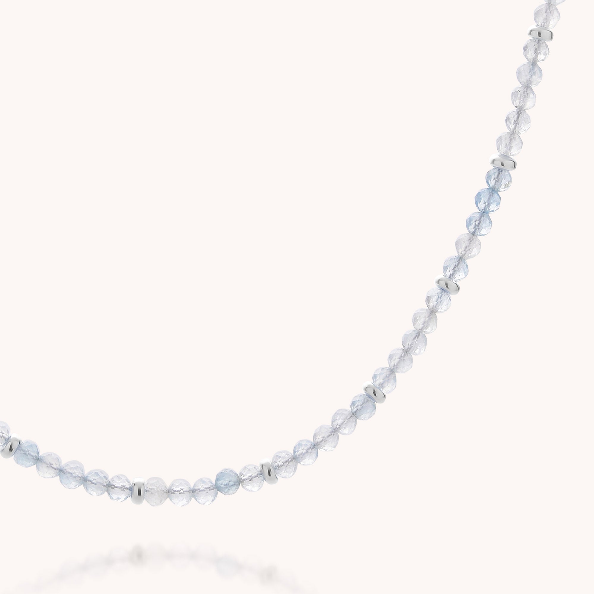 The Aquamarine March Birthstone Orbit Necklace features delicate, faceted clear beads and a few evenly spaced silver accents, gracefully curving against a plain white background—an exquisite handcrafted jewelry piece perfect for celebrating those with a March birthday.