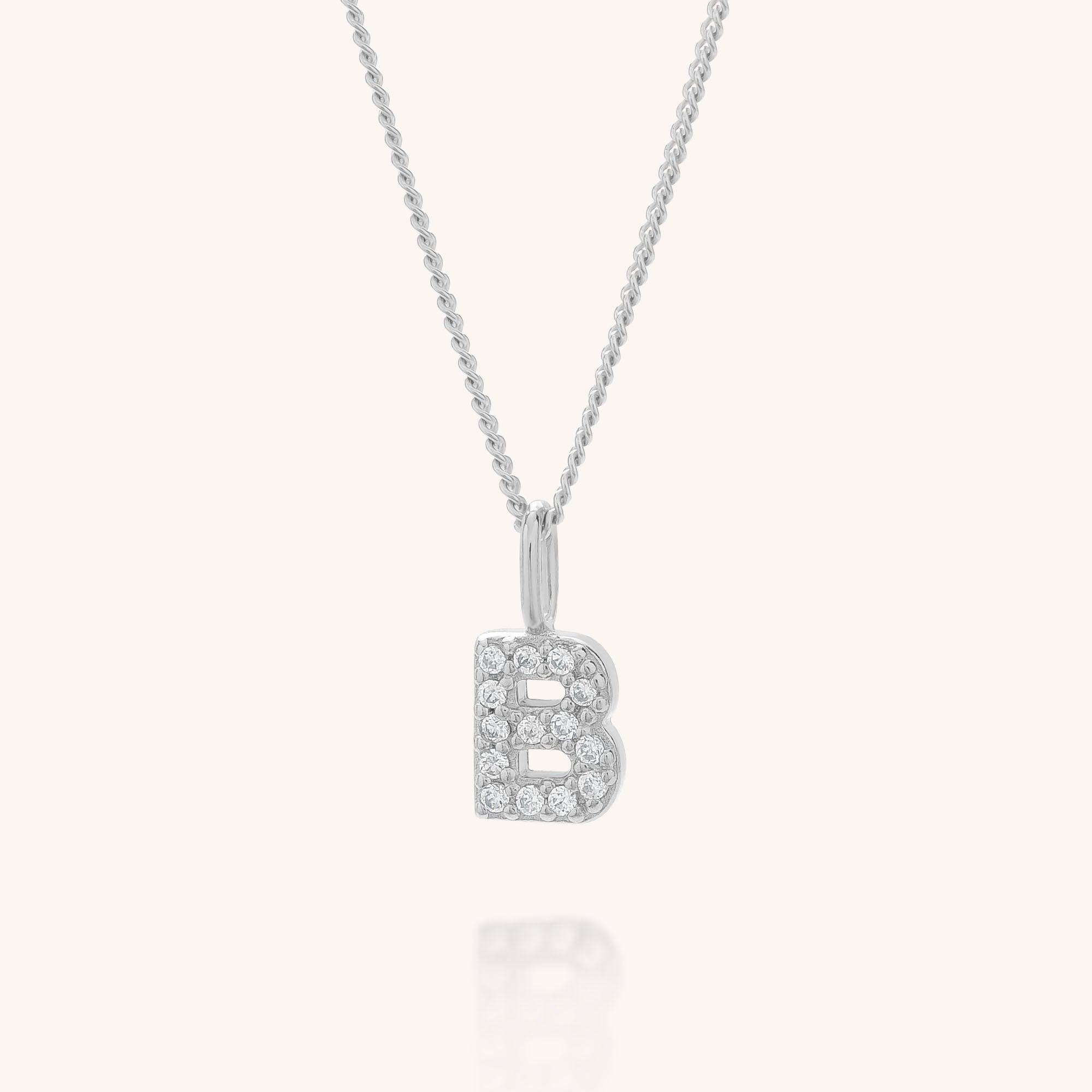 The Initial Sparkle Necklace, featuring a silver letter “B” pendant adorned with sparkling cubic zirconia stones, is displayed on a plain white background.