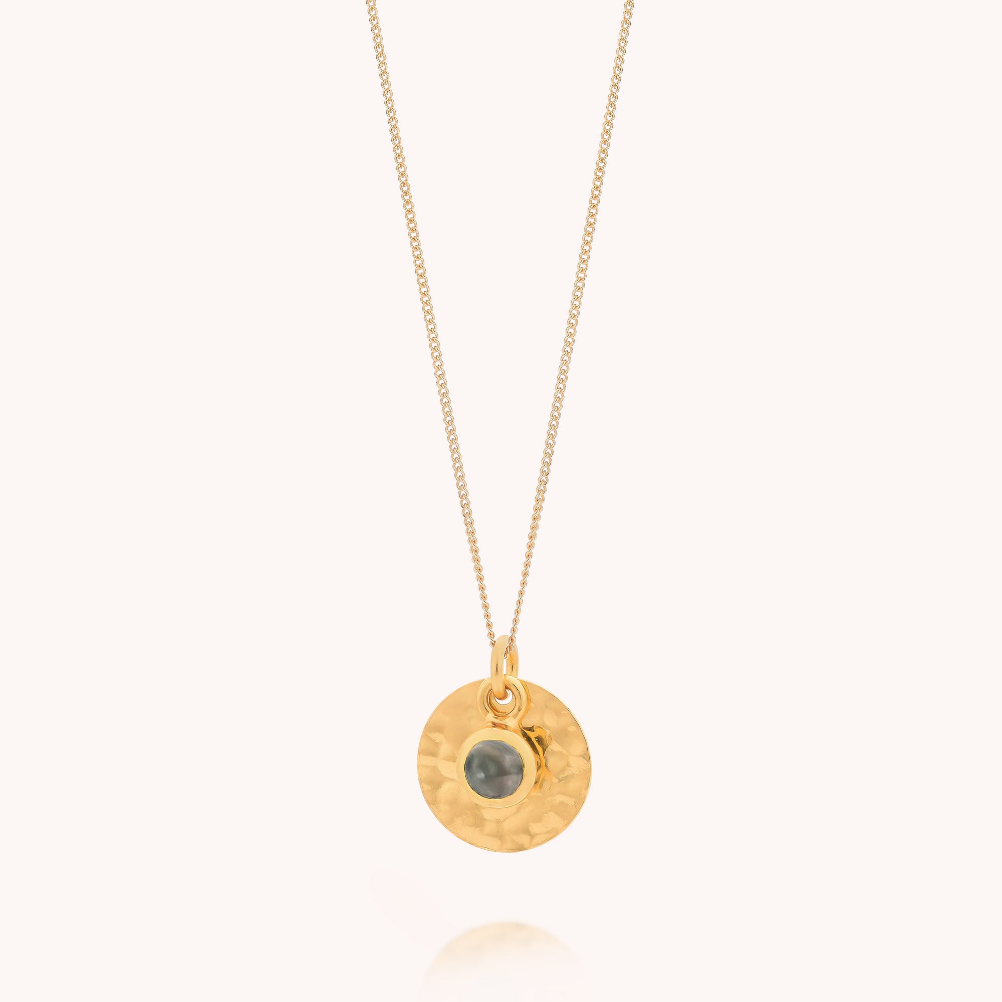 Blue Topaz Luna Disc Necklace with a hammered round pendant featuring a small blue topaz gemstone in the center—evoking the charm of a December birthstone—displayed on a light background.