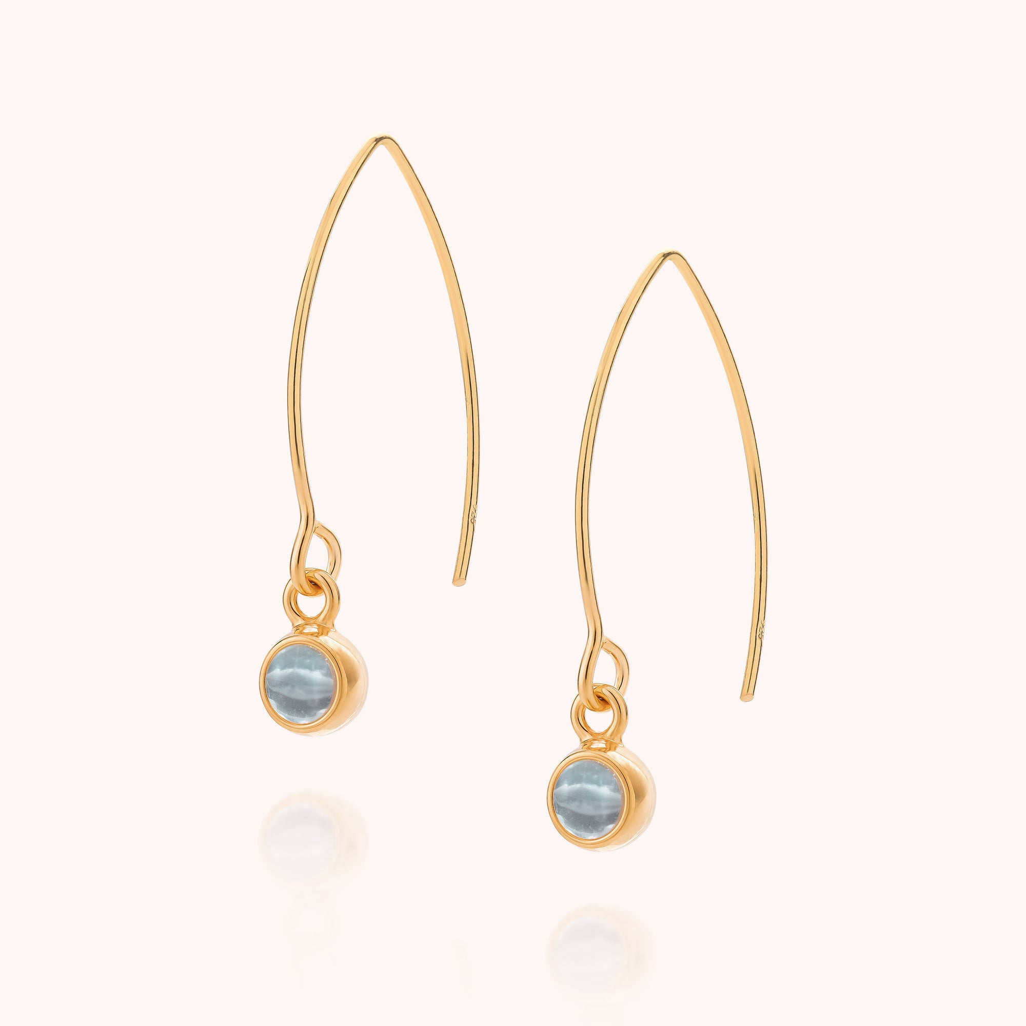 Blue Topaz Gem Dot Arc Earrings with a curved wire design, each showcasing a small round blue topaz—December's birthstone—bezel-set at the base, displayed on a plain light background. These elegant gemstone drop earrings are perfect for adding a subtle pop of color to any outfit.
