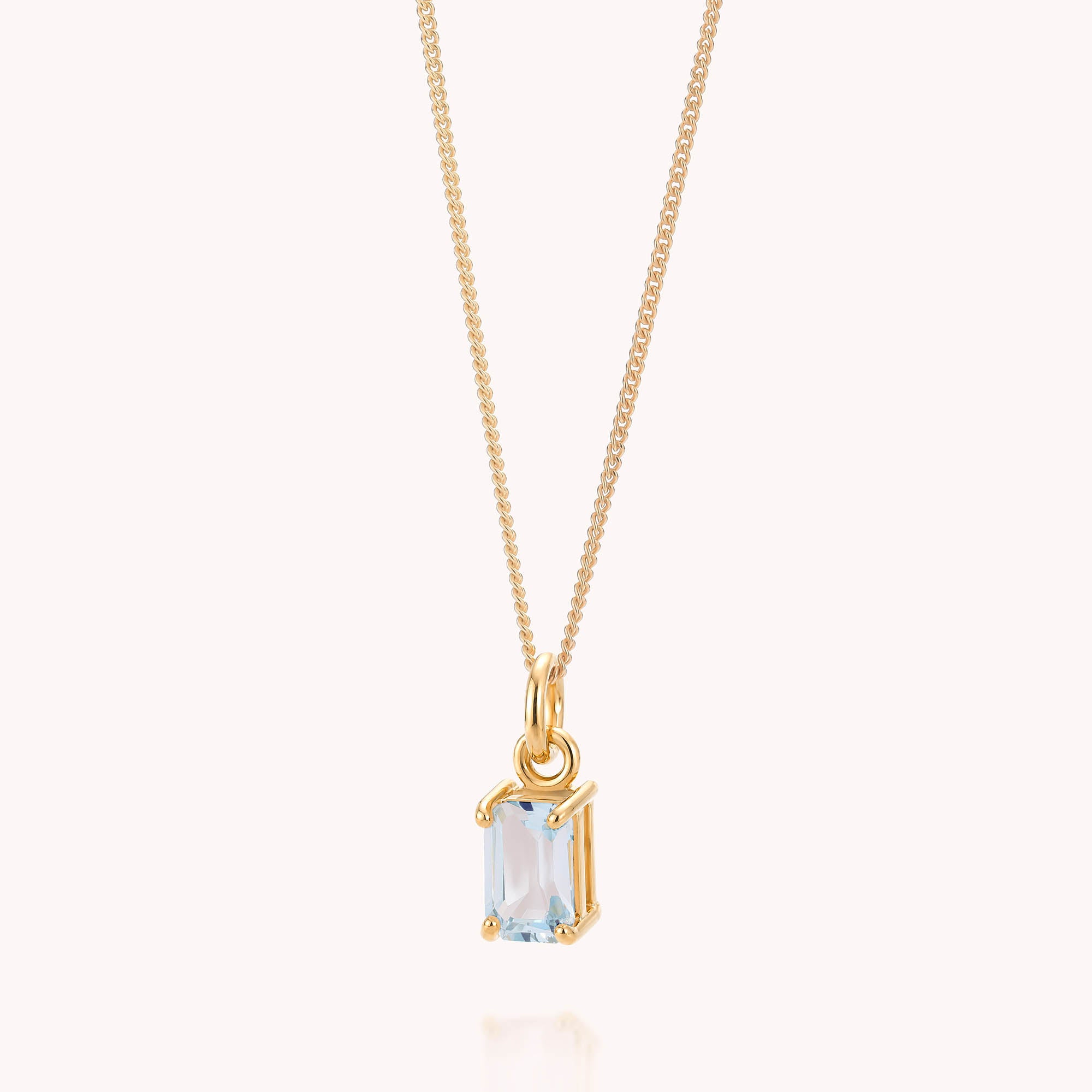 The Blue Topaz Octavia Necklace features a gold chain with an octagonal light blue topaz pendant set in a gold frame—showcasing the stunning December birthstone against a plain white background.