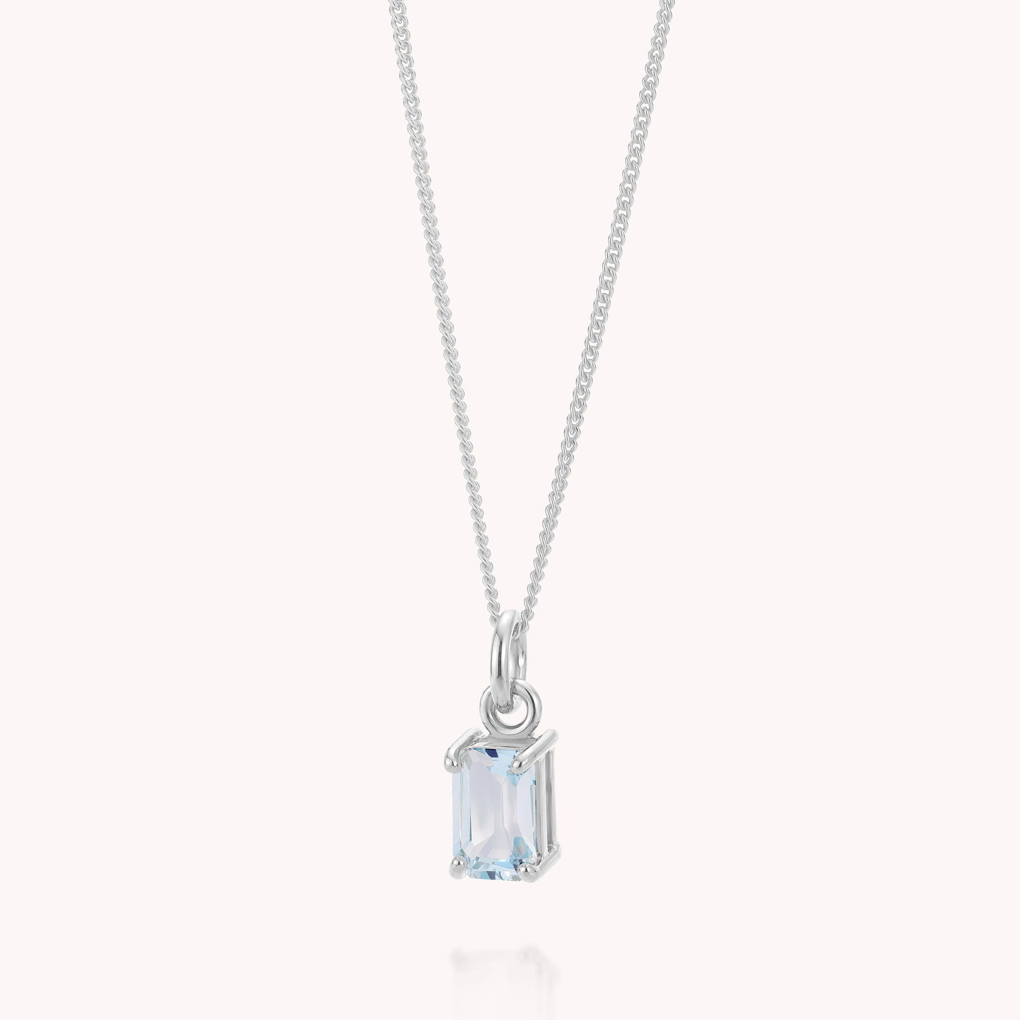 Introducing the Blue Topaz Octavia Necklace—a delicate silver necklace with a slender chain adorned by an octagonal pendant set with a light blue topaz in a minimalist four-prong setting. This elegant piece, ideal as a December birthstone gift, is beautifully showcased against a plain white background.