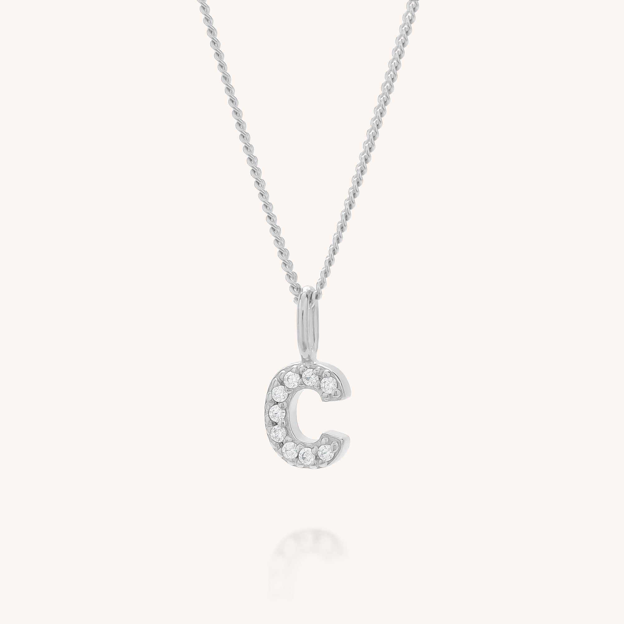 The Initial Sparkle Necklace is a personalised silver necklace with a C-shaped pendant embellished with sparkling cubic zirconia, elegantly showcased on a simple light background.