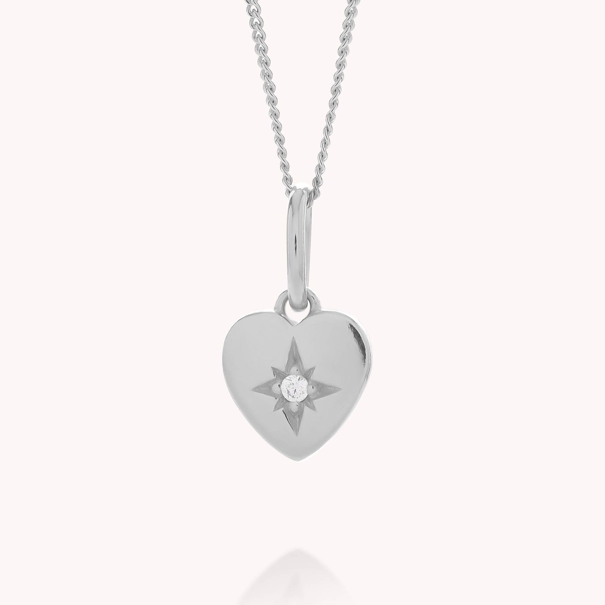 Introducing the Wish Heart Necklace—a beautifully crafted silver heart-shaped pendant featuring a starburst design and a petite central gemstone. Made from eco sterling silver, this elegant necklace hangs gracefully from a delicate silver chain, set against a plain white background to highlight its timeless appeal and commitment to sustainability.