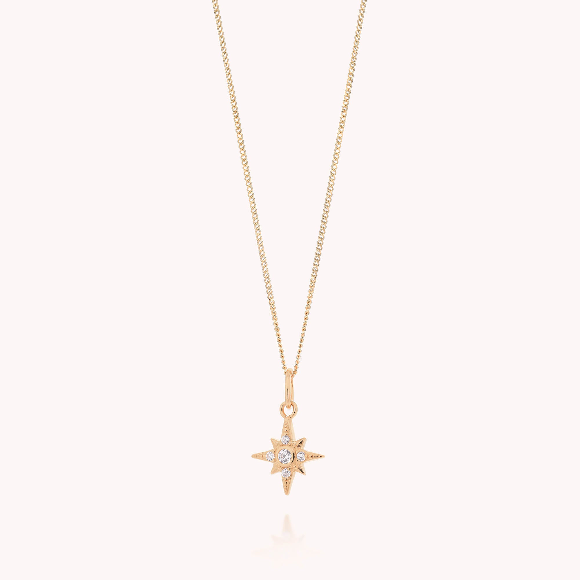 The Celestial Star Necklace is a gold layered piece featuring a delicate chain and a star-shaped pendant embellished with sparkling cubic zirconia gemstones, displayed against a plain white background.