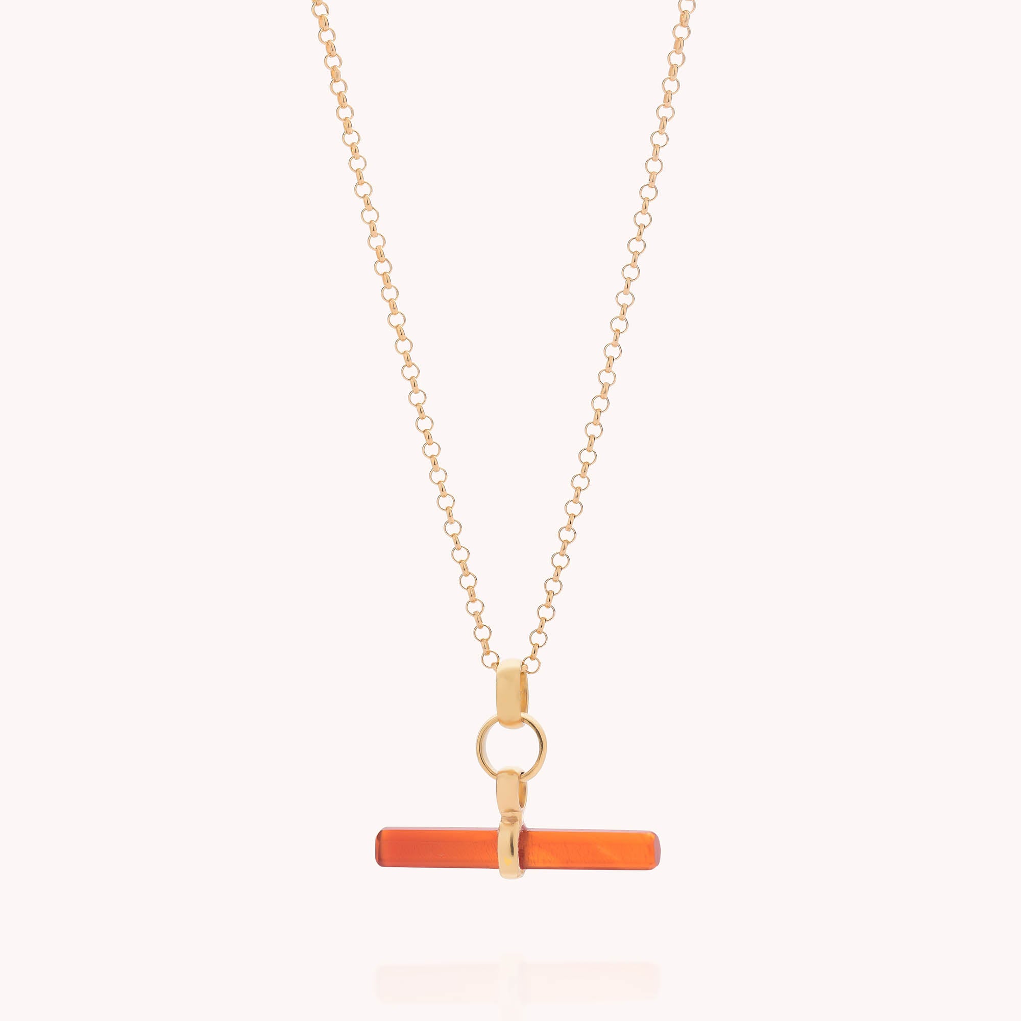 The Gemstone T Bar Necklace features a horizontal, rectangular orange bar pendant with gold accents, evoking a sleek T-bar design, and is displayed against a simple light background.