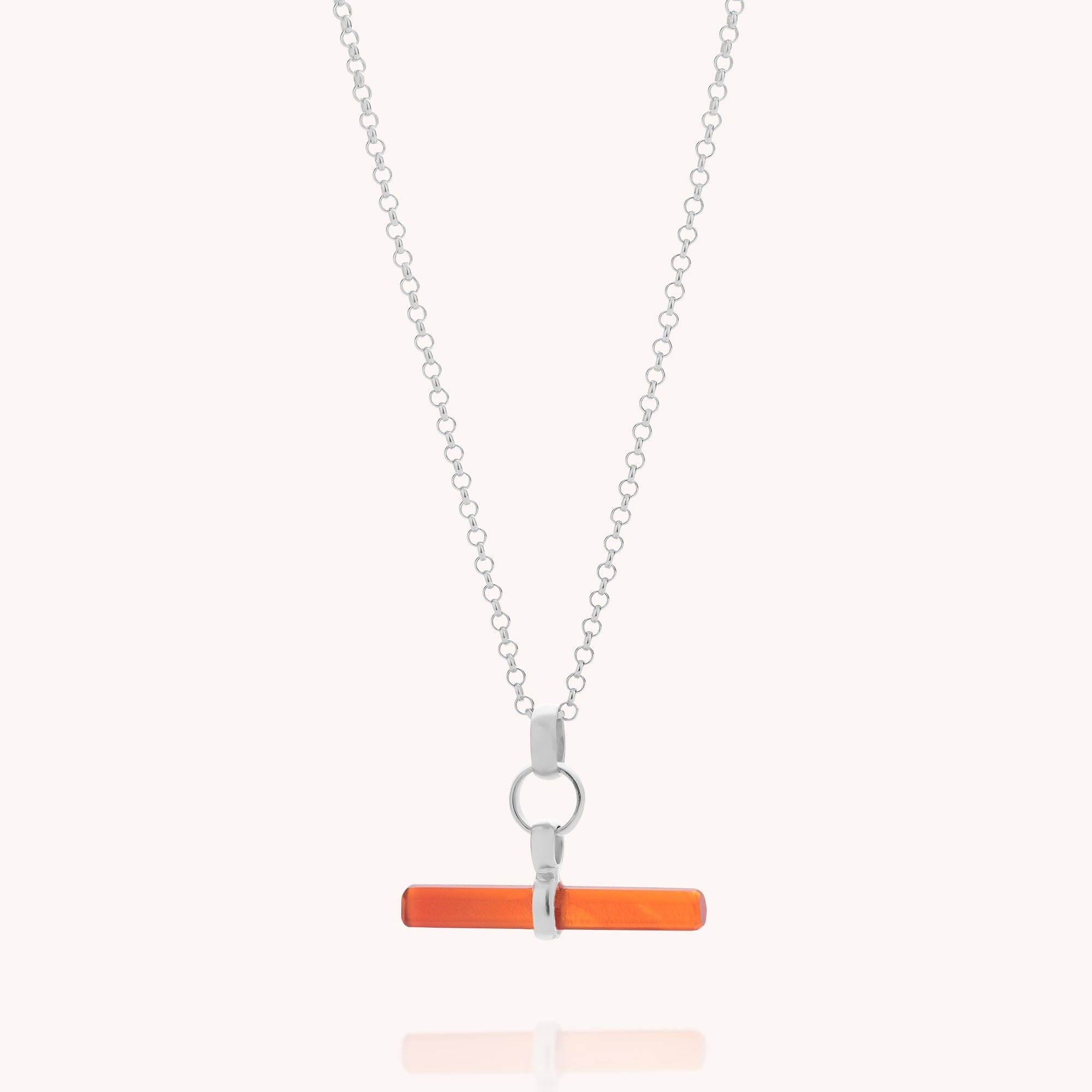 The Carnelian T-Bar Necklace features a horizontal orange carnelian pendant suspended from a silver chain by a circular link, beautifully highlighting the vivid charm of gemstone jewellery against a simple light backdrop.