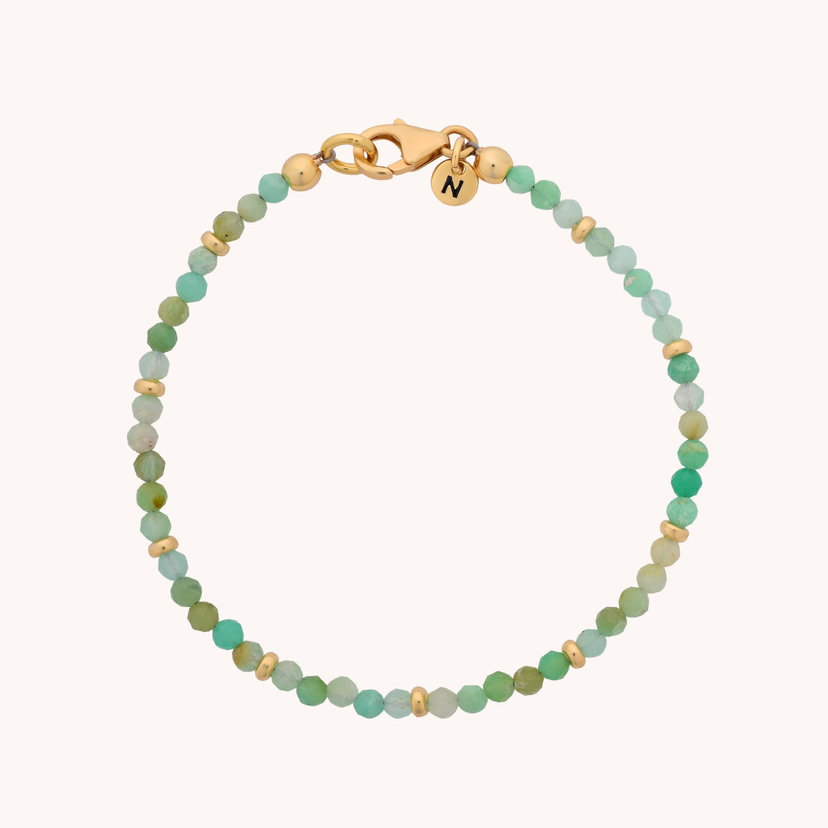 Introducing the Chrysoprase Orbit Bracelet - May: a delicate handcrafted piece featuring small round green chrysoprase beads accented with gold touches. Complete with a gold lobster clasp and a petite gold charm engraved with the letter N, this gemstone bracelet is thoughtfully designed as meaningful jewelry—making it an ideal gift for anyone celebrating a May birthstone.