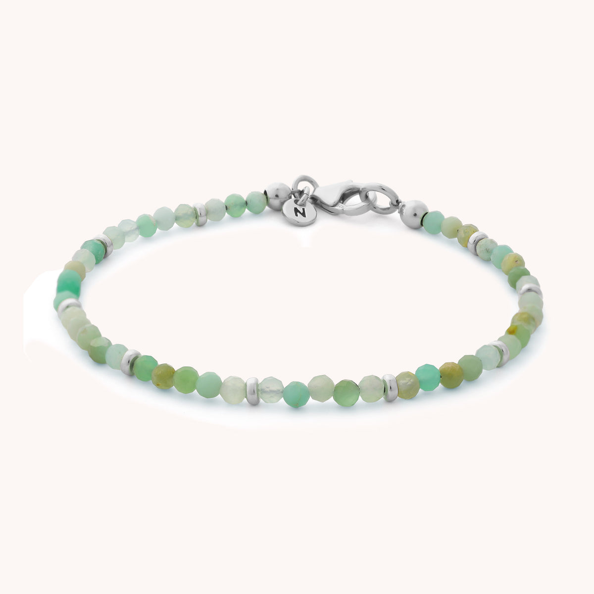 The Chrysoprase Orbit Bracelet - May is a beautiful piece of handcrafted gemstone jewelry, featuring delicate green and white round beads with a silver clasp and a small charm.