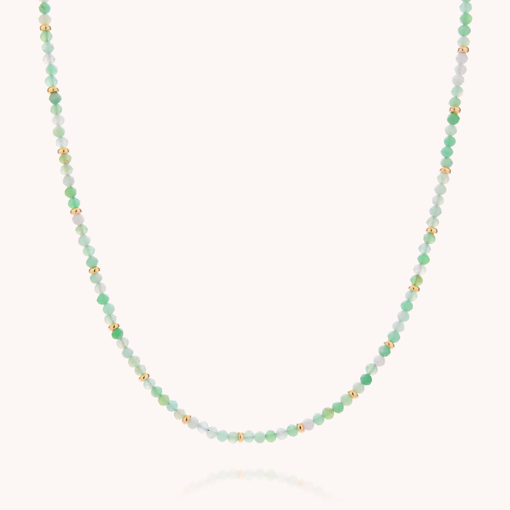 The Chrysoprase May Birthstone Orbit Necklace is a delicate, handcrafted piece featuring alternating small green, light blue, and gold beads—including chrysoprase, the May birthstone—elegantly displayed against a plain white background.