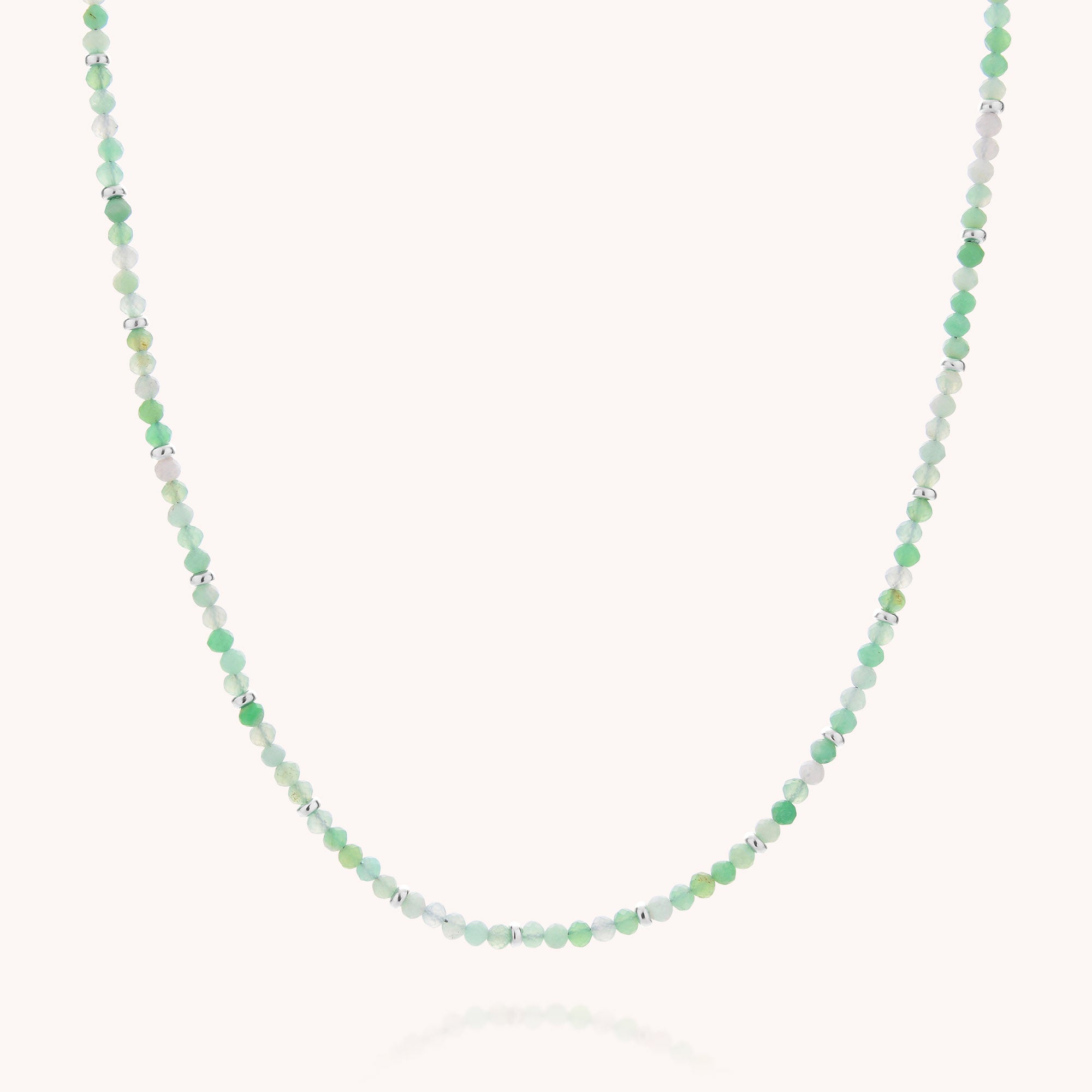 The Chrysoprase May Birthstone Orbit Necklace features small, round chrysoprase beads in varying shades of green and white, artfully spaced along a slender, nearly invisible strand. Displayed on a plain white background, this handcrafted necklace gracefully showcases the tranquil allure of May’s birthstone.