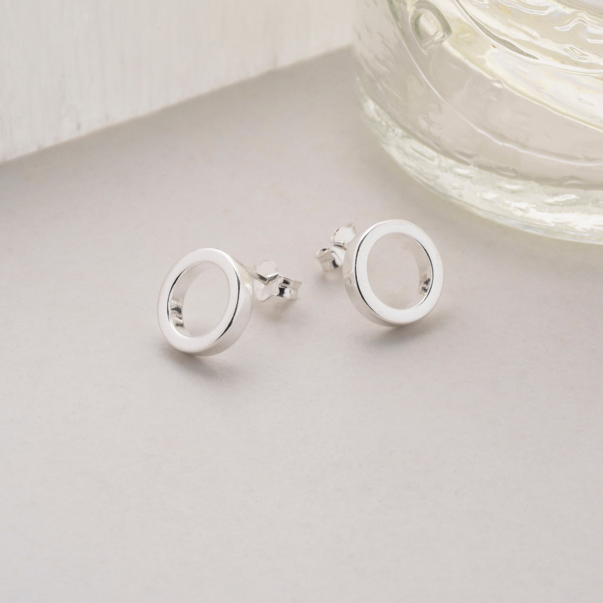 pair of circle earstuds next to a vase